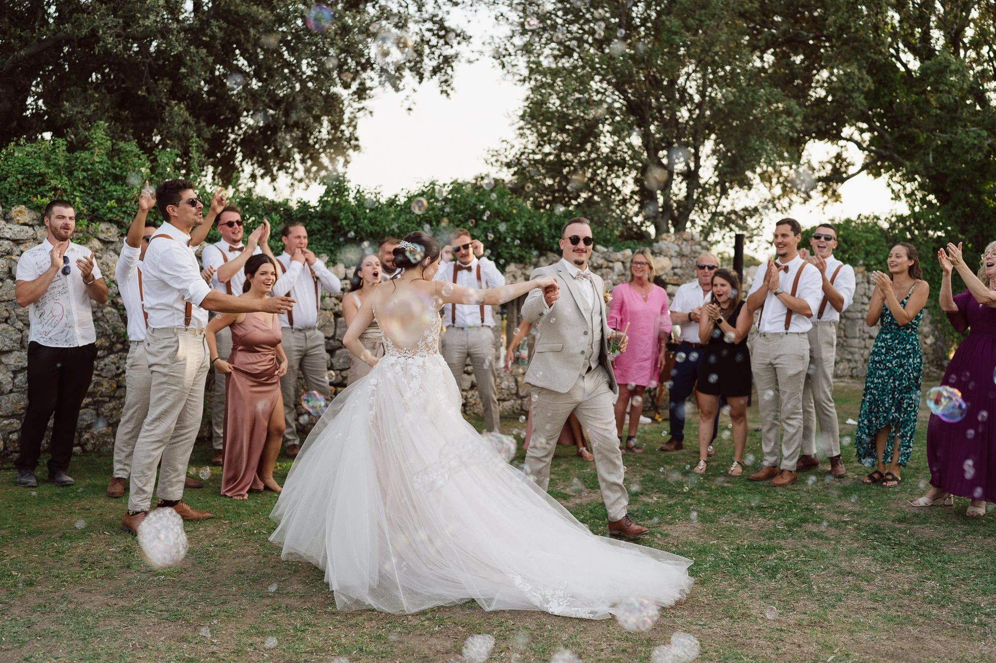 Première danse des mariés en extérieur au Domaine de Sarson en Provence, entourés de leurs invités qui applaudissent, bulles dans l’air et ambiance festive au coucher du soleil.