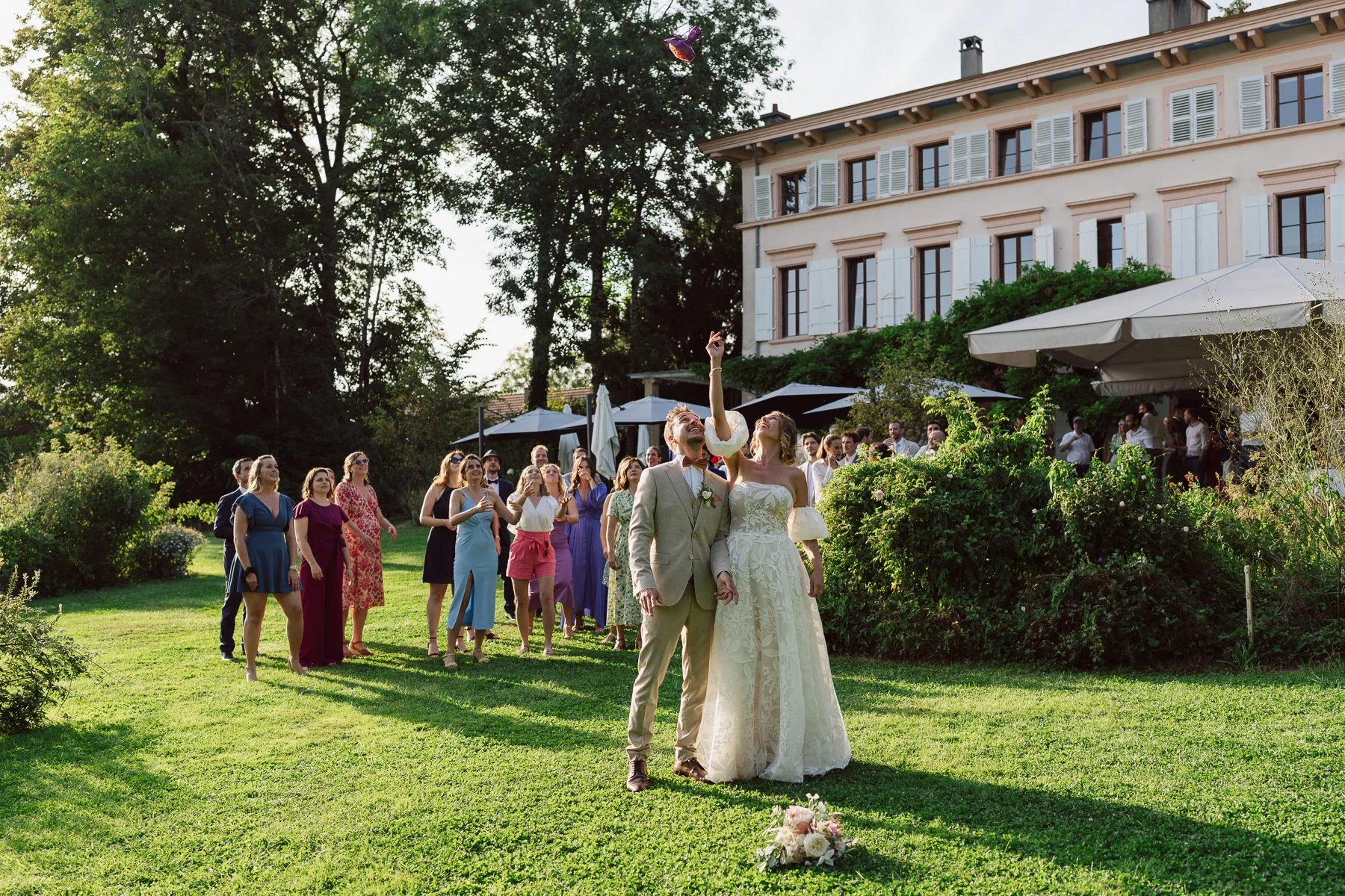 Lancer du bouquet dans le jardin du Castel Bois-Genoud, entourés de leurs invités, lors du mariage de Diana et Loïc.