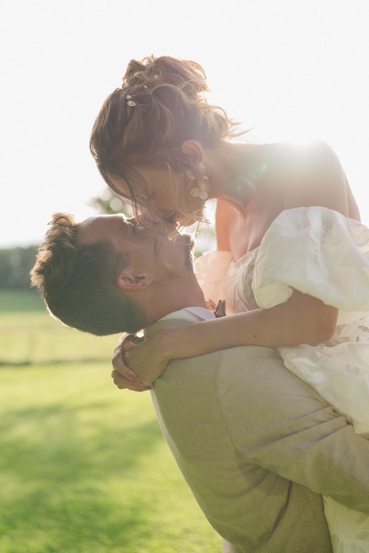 Moment de tendresse entre les mariés après la cérémonie, baignés de lumière naturelle dans le parc du Castel de Bois-Genoud