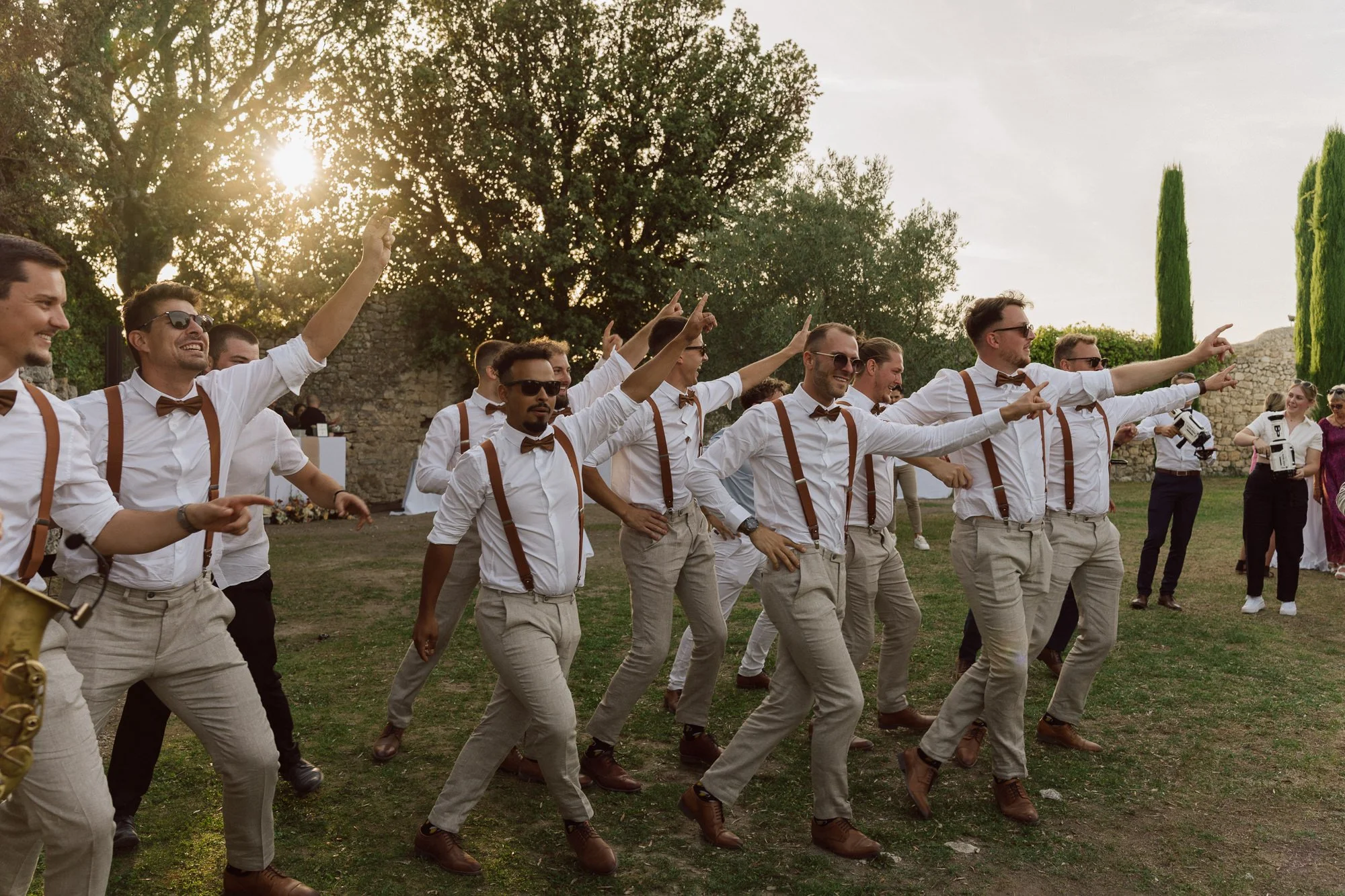 Entrée festive et chorégraphiée des garçons d’honneur lors d’un mariage au Domaine de Sarson en Provence, ambiance joyeuse en extérieur au coucher du soleil.