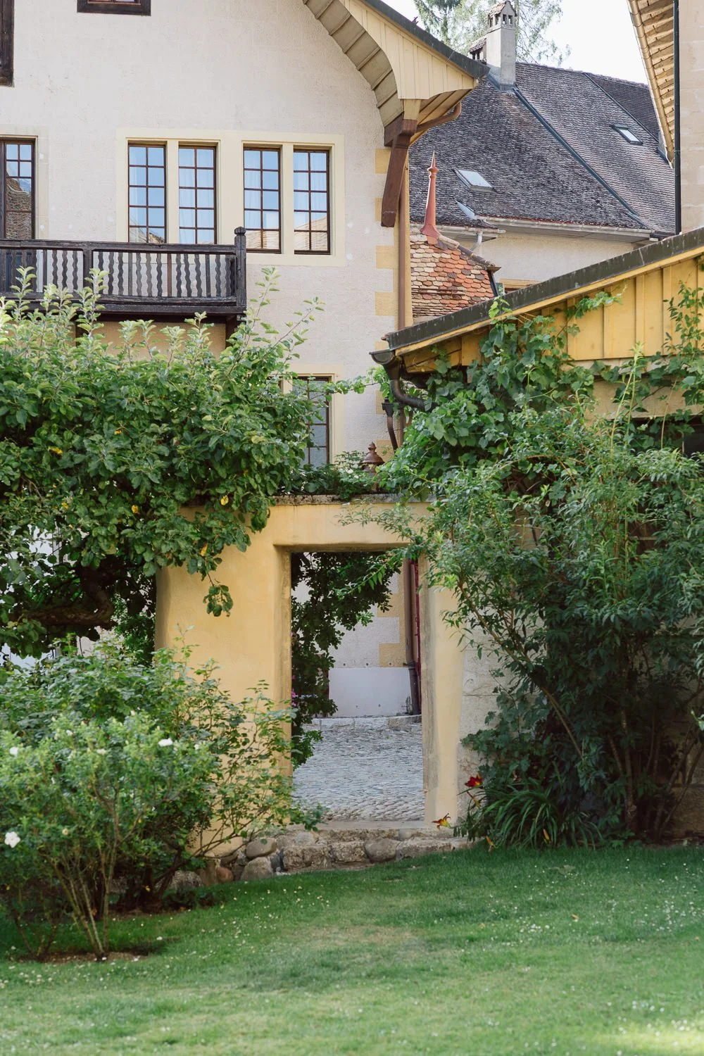 Passage en pierre et verdure au Jardin Baillival à Romainmôtier, architecture historique et jardin soigné, cadre paisible et authentique pour un mariage en Suisse, photo par Nonante Émotions.