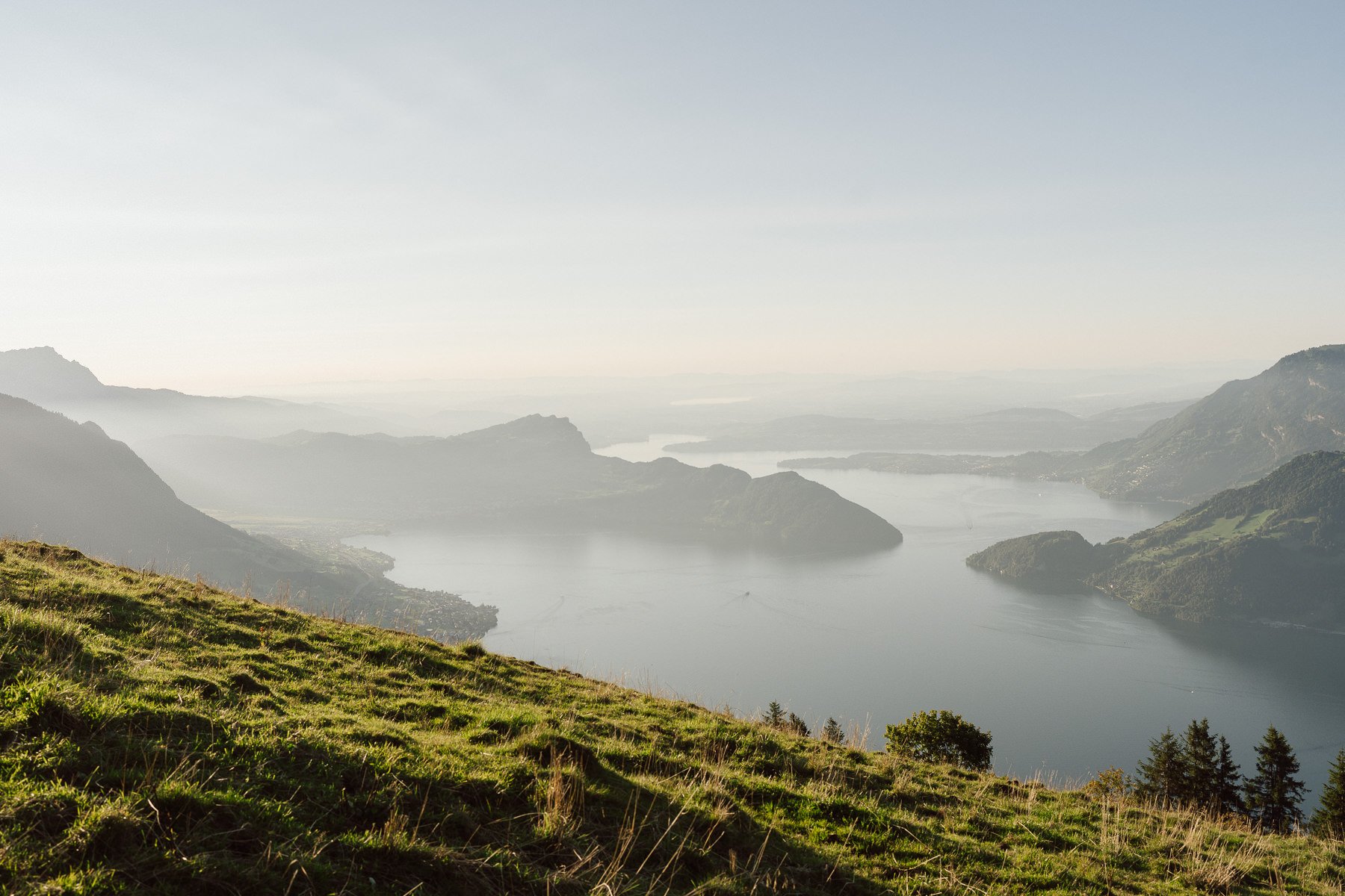 Vue en hauteur sur un lac entouré de montagnes suisses dans une lumière douce – décor de mariage en Suisse par Nonante Émotions