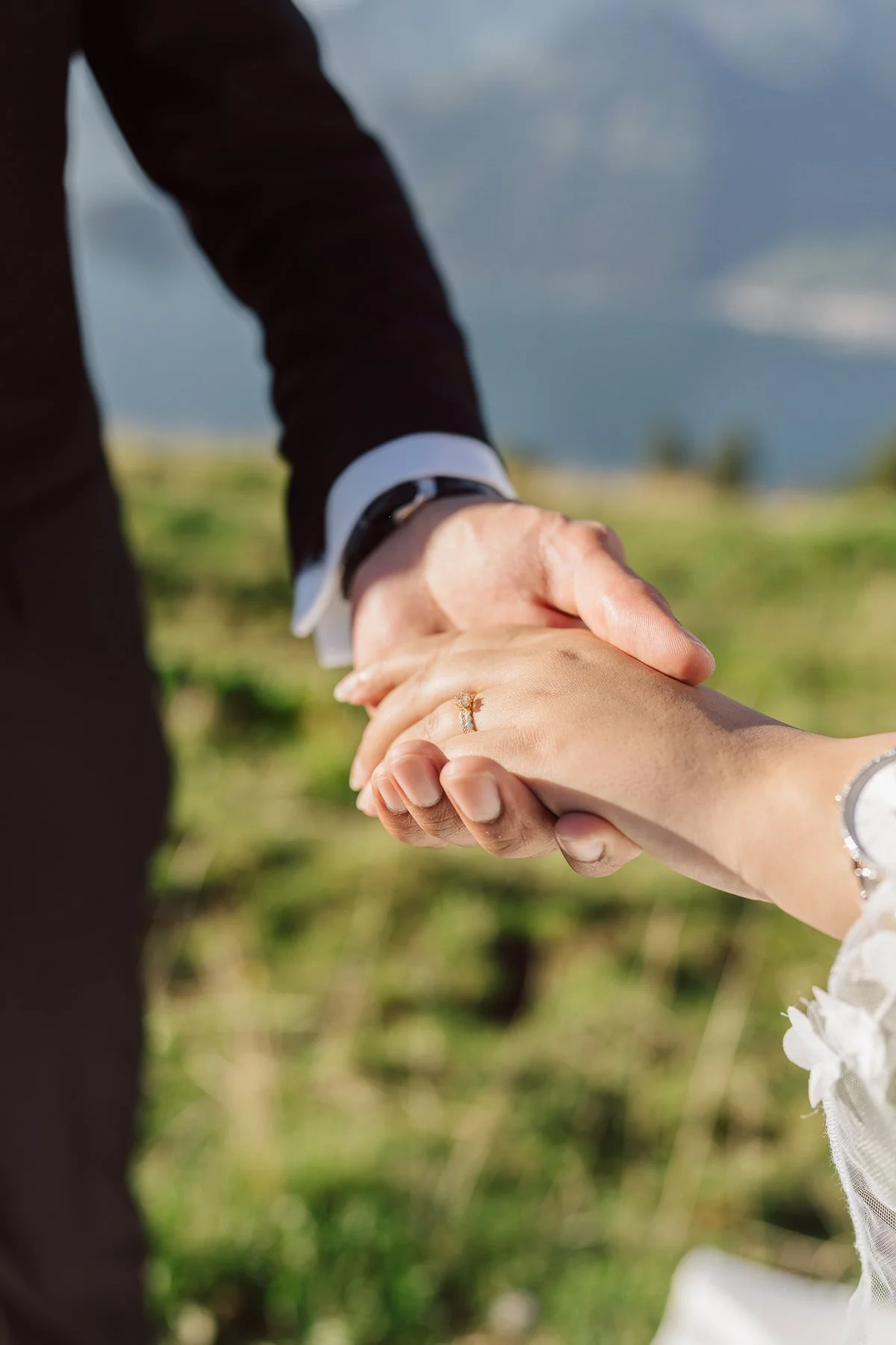 Gros plan sur les mains des mariés avec alliance et bague de fiançailles en montagne – détail romantique mariage par Nonante Émotions