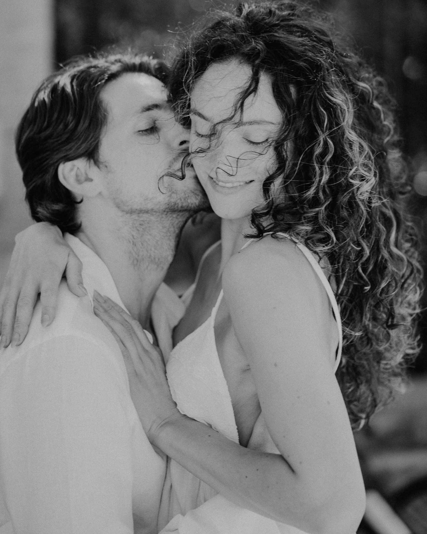 Un couple souriant en embrassant, en noir et blanc.