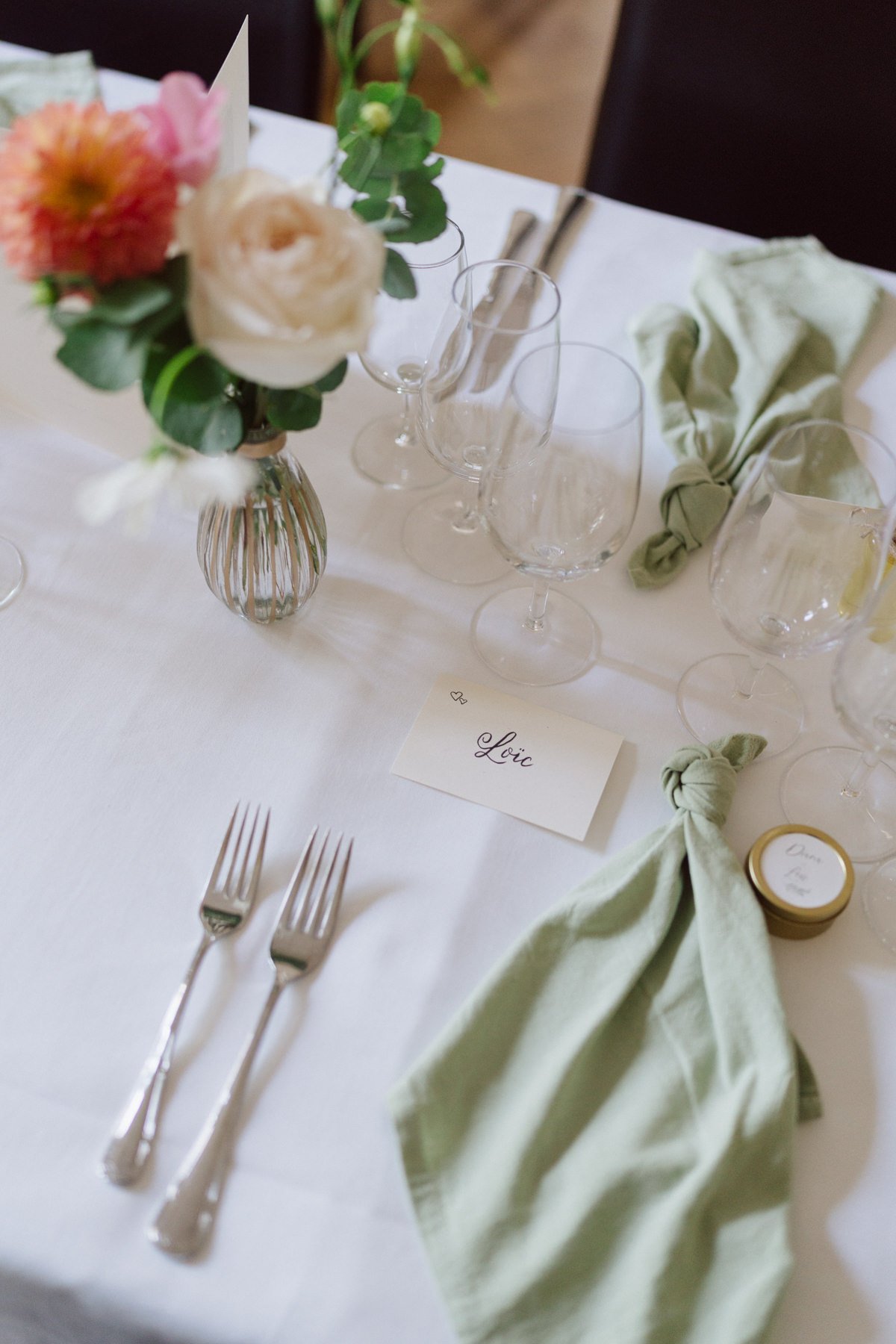 Détail de la décoration de table de mariage avec fleurs, verrerie et marque-place lors de la réception au Castel de Bois-Genoud