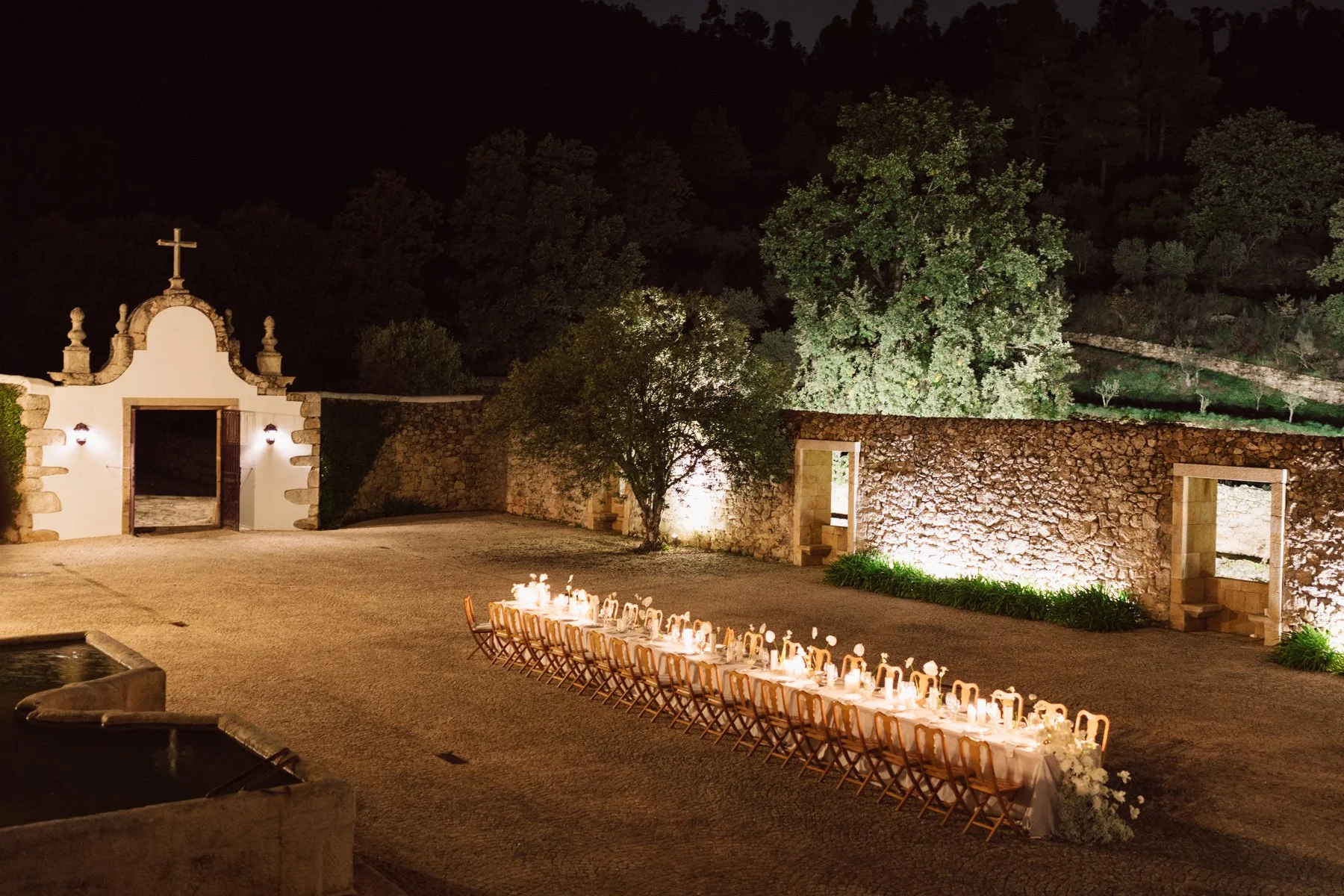 Réception de mariage de nuit à la Quinta do Pinho au Portugal, longue table éclairée aux bougies dans la cour du domaine – photo Nonante Emotions.
