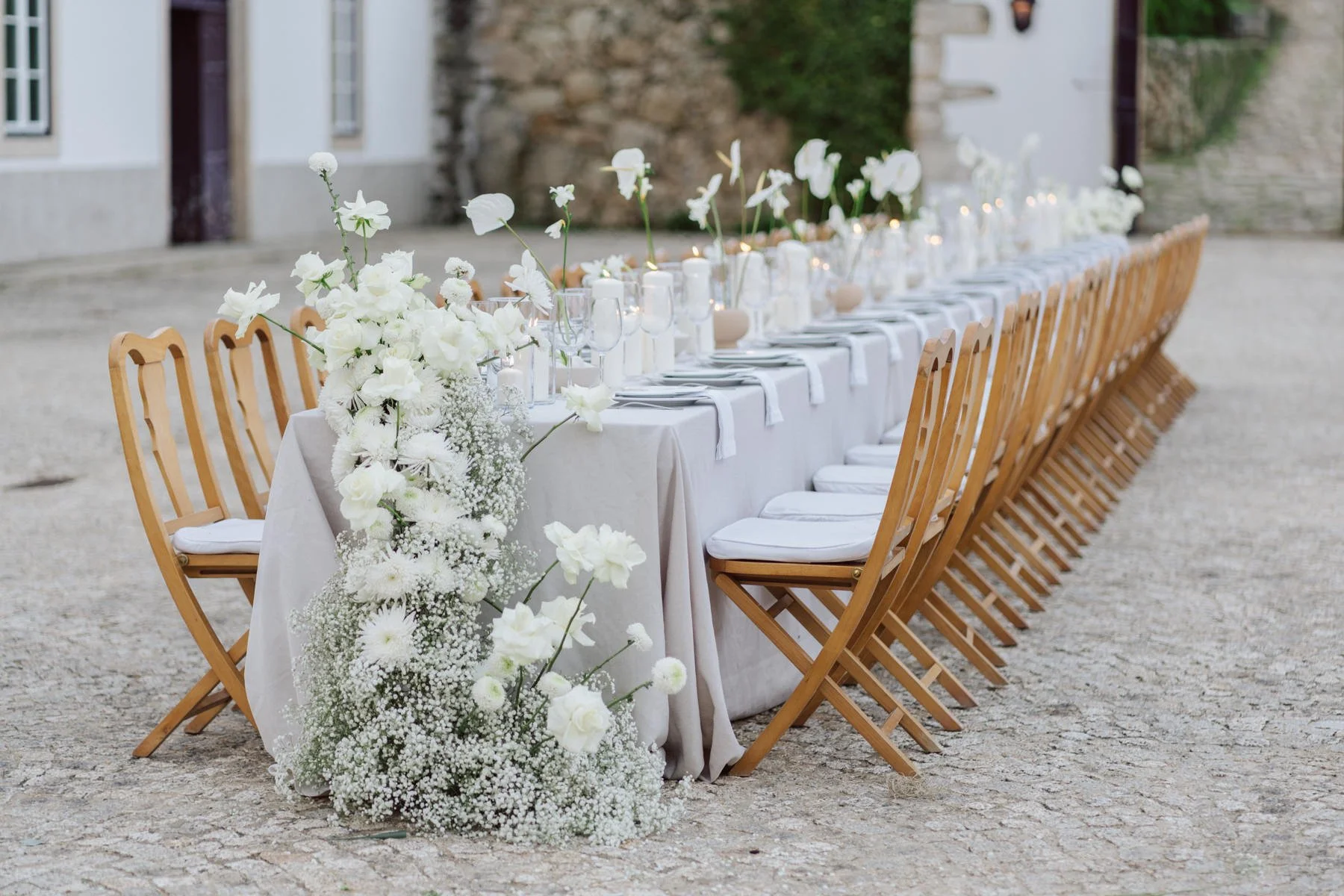 Détail d’une longue table de mariage fleurie à la Quinta do Pinho au Portugal avec chaises en bois et décoration élégante