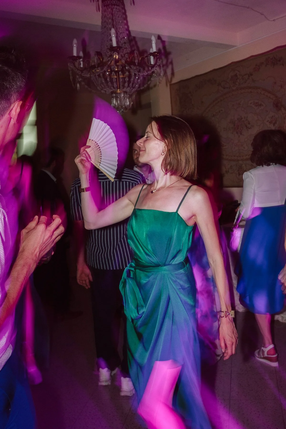 Invitée en robe verte dansant pendant la soirée de mariage en Toscane, ambiance festive avec lumières colorées