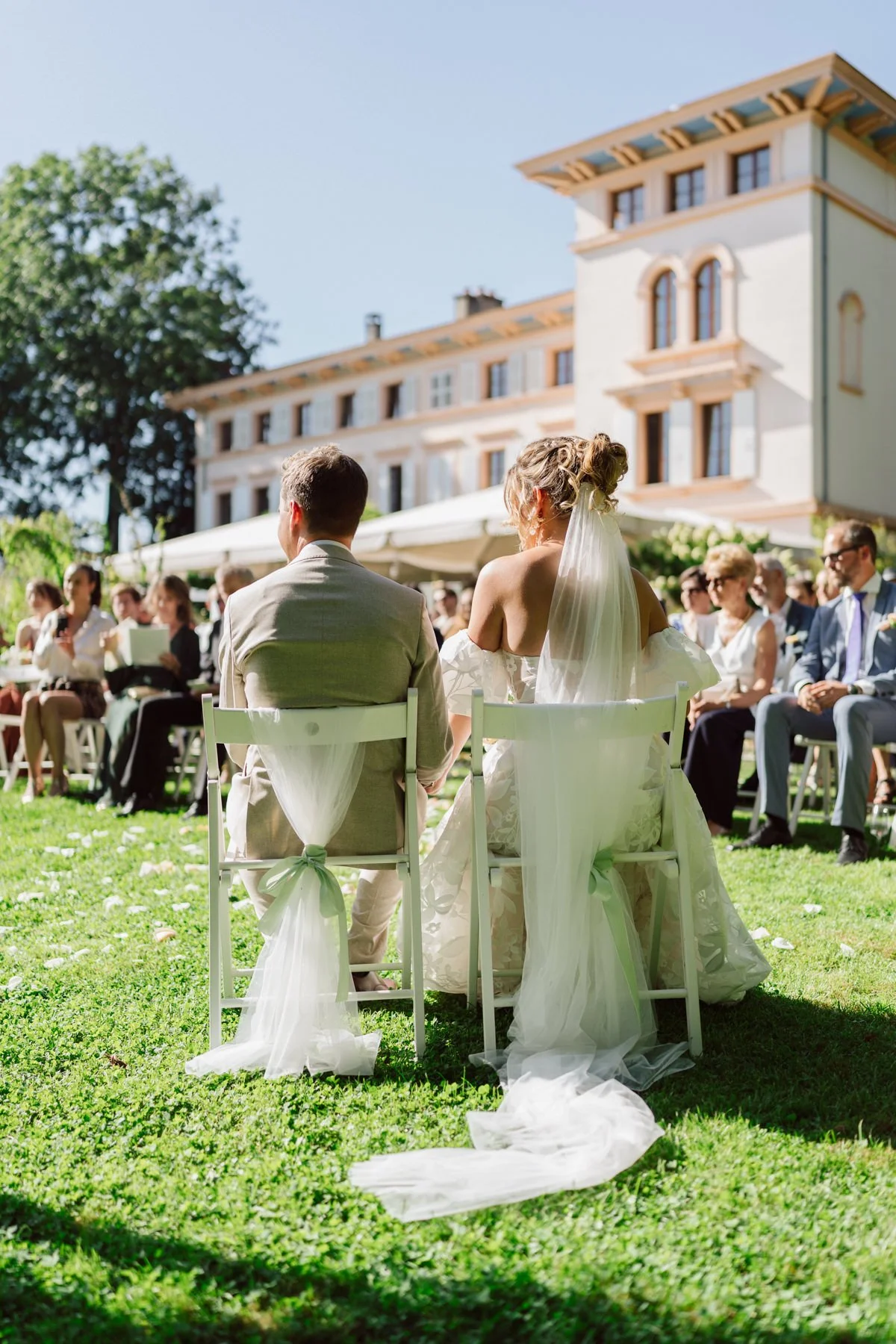 Vue arrière des mariés lors de leur cérémonie de mariage en plein air au Castel de Bois-Genoud