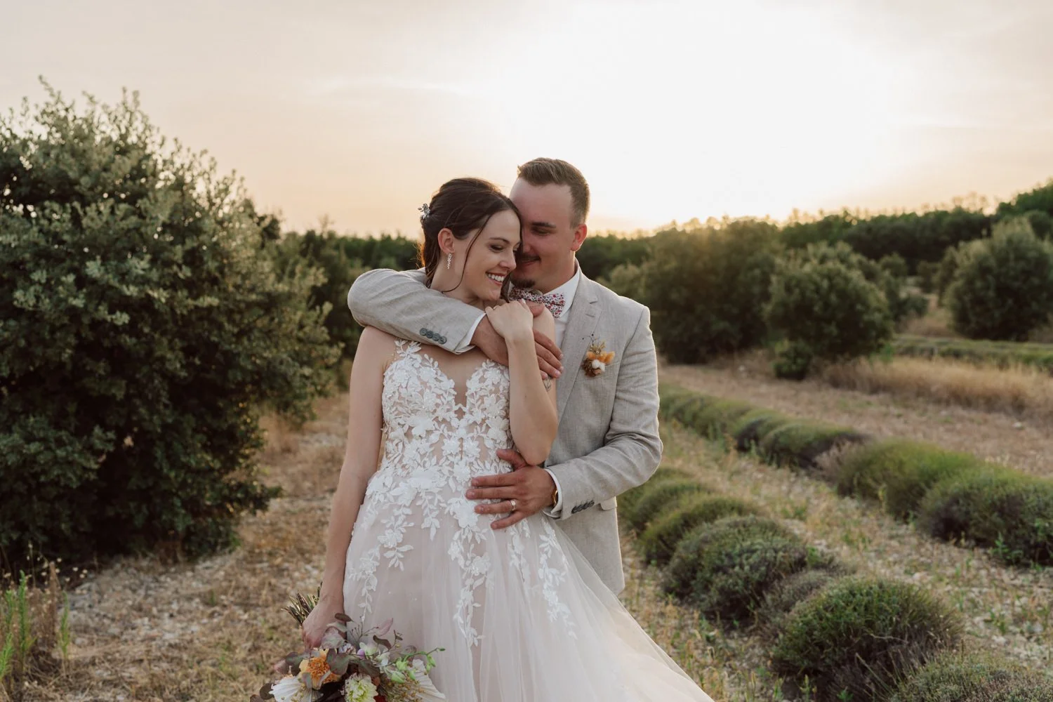 Portrait tendre des mariés enlacés au coucher du soleil dans la campagne provençale au Domaine de Sarson.