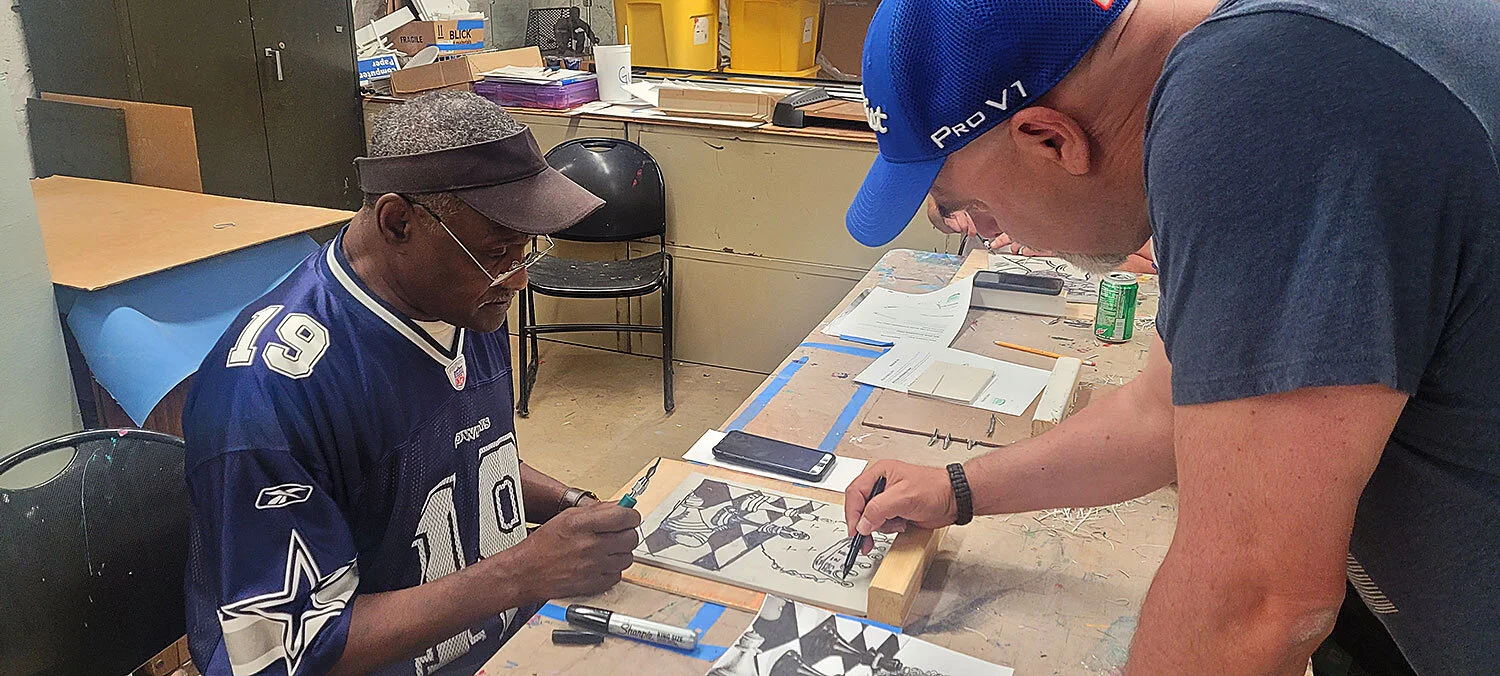 Michael Weatherly helps Eddie from the Matthew House with his printmaking project.