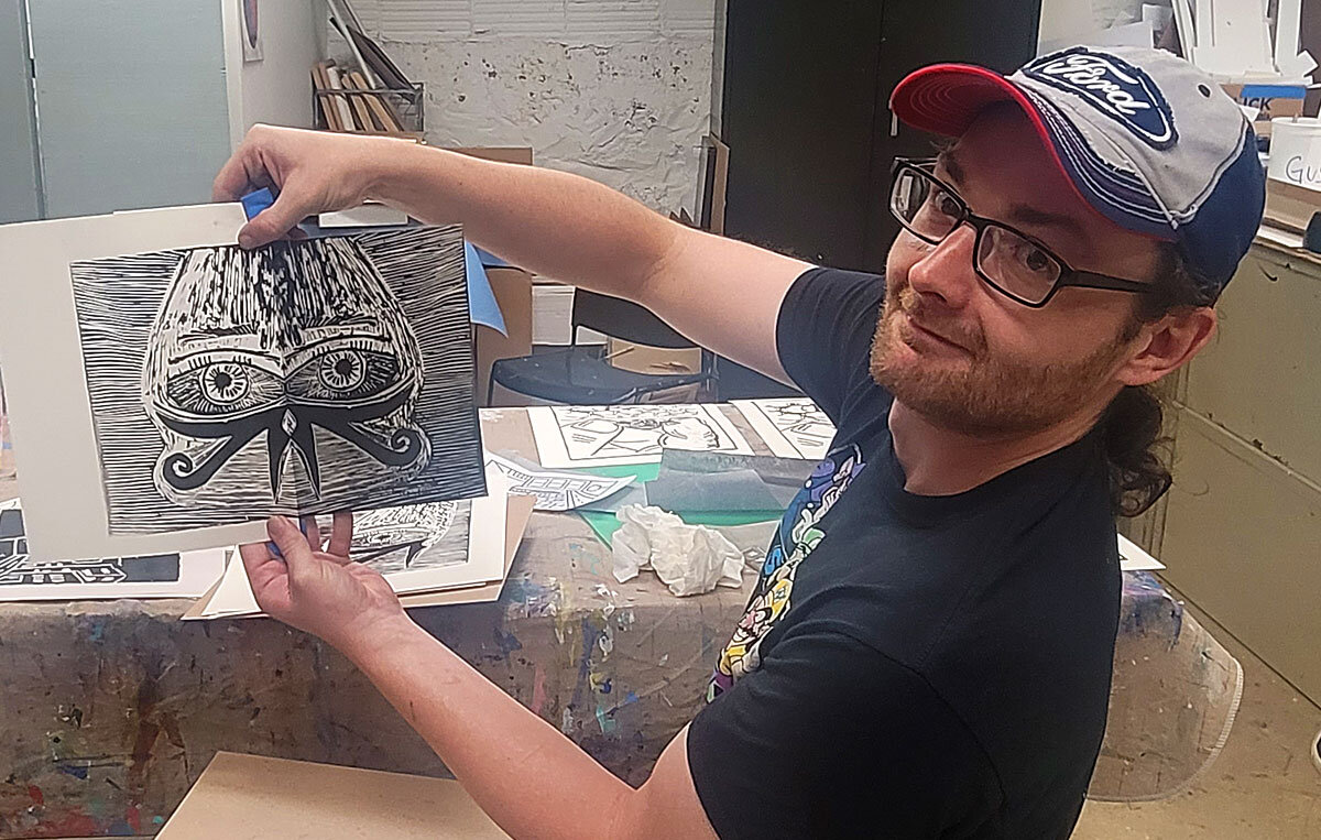  One of the men displays his finished print in class.  