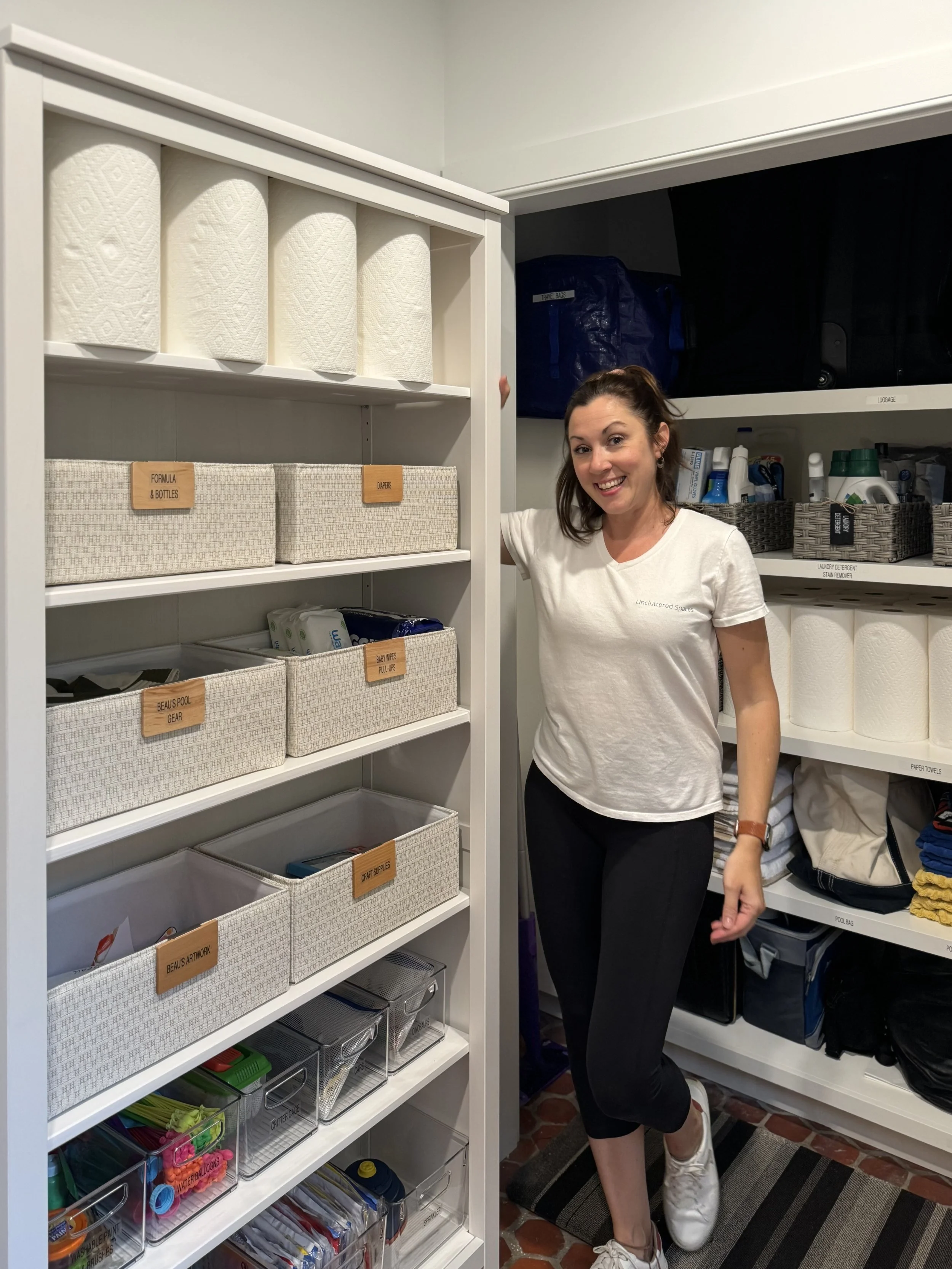 A woman stands next to a neatly organized shelf with home supplies