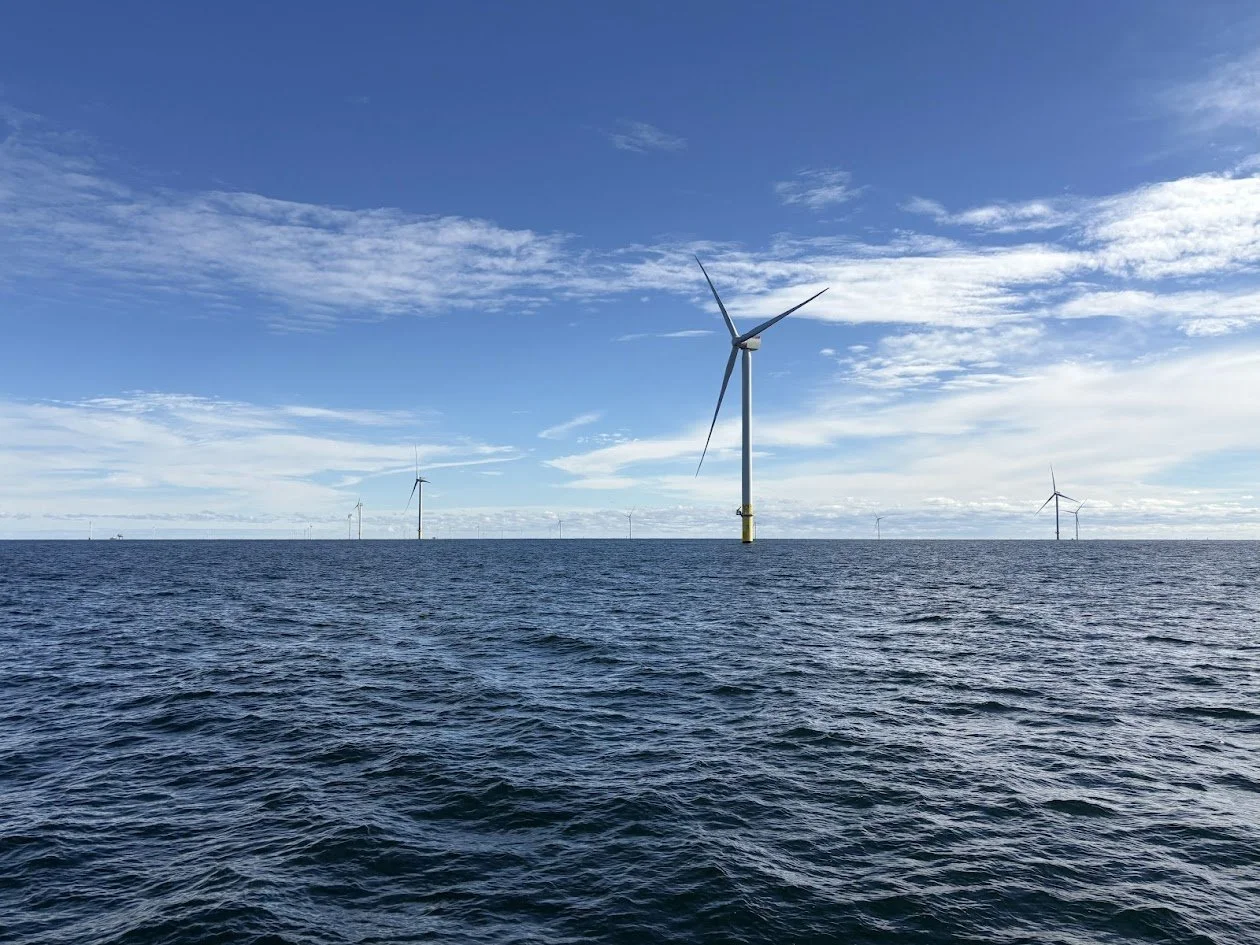 Offshore wind turbines in the ocean under a partly cloudy sky.