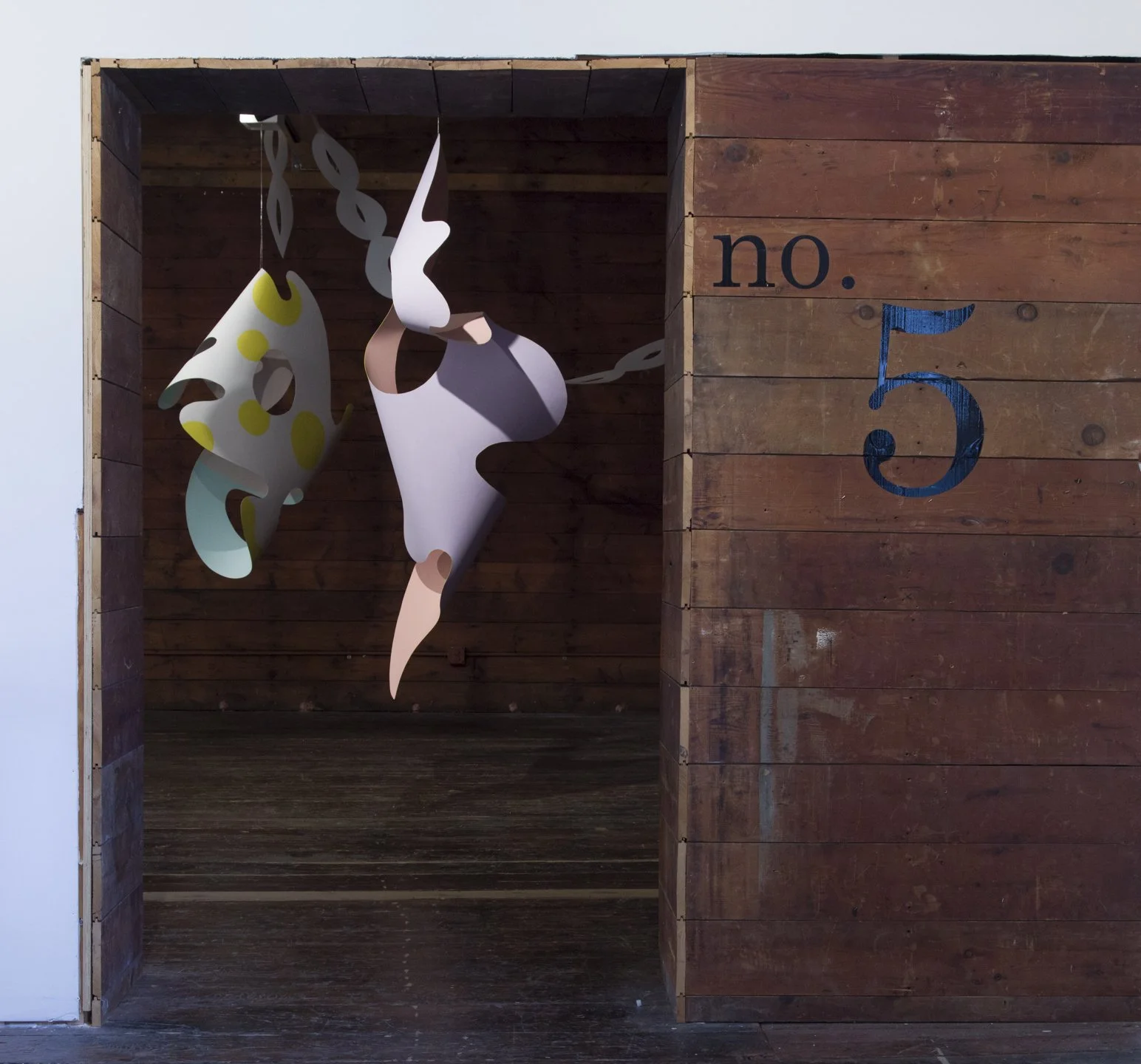 Wooden booth with hanging abstract shapes, numbered 'no. 5' on the side.