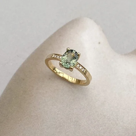 green sapphire engagement ring with small diamonds in recycled gold band