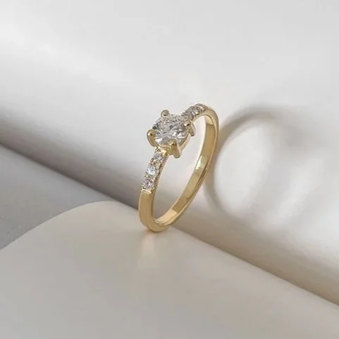 Handgemaakte klassieke verlovingsring met ronde diamant en kleine diamantjes aan de zijkanten. Handgemaakt door goudsmid De Vree te Antwerpen.