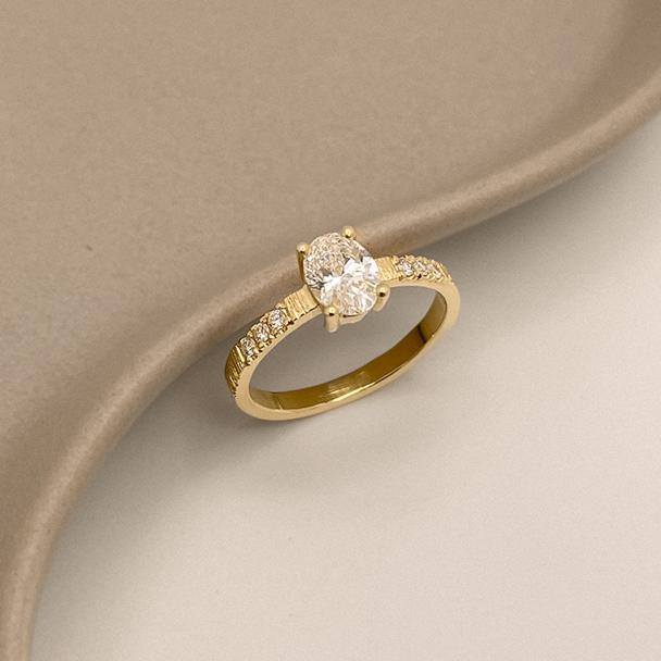 Ovale diamanten verlovingsring Antwerpen. Gestructureerde ringband met kleine diamanten aan de zijkanten.