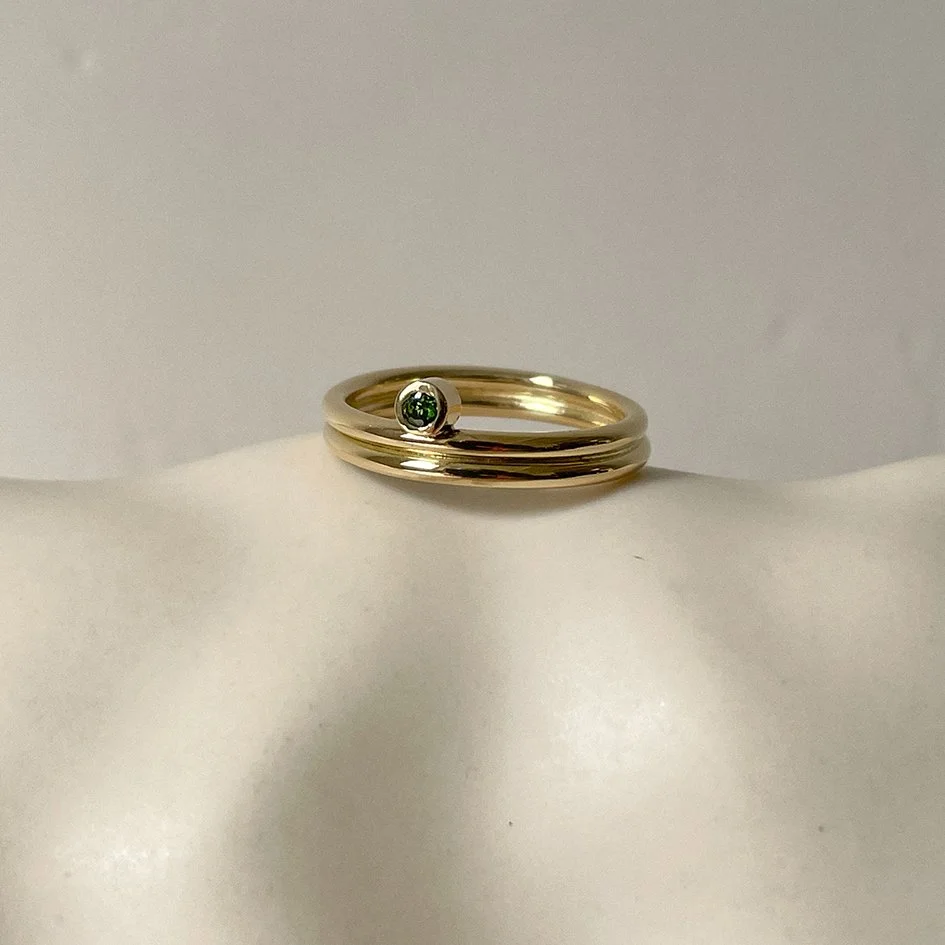 A simple, elegant engagement ring featuring a small green gemstone