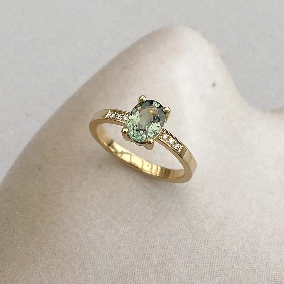 Green sapphire engagement ring in 18K yellow gold featuring small diamonds on the side