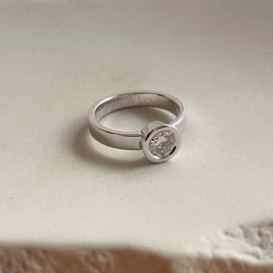 Modern wide engagement ring with a round setting in recycled white gold 