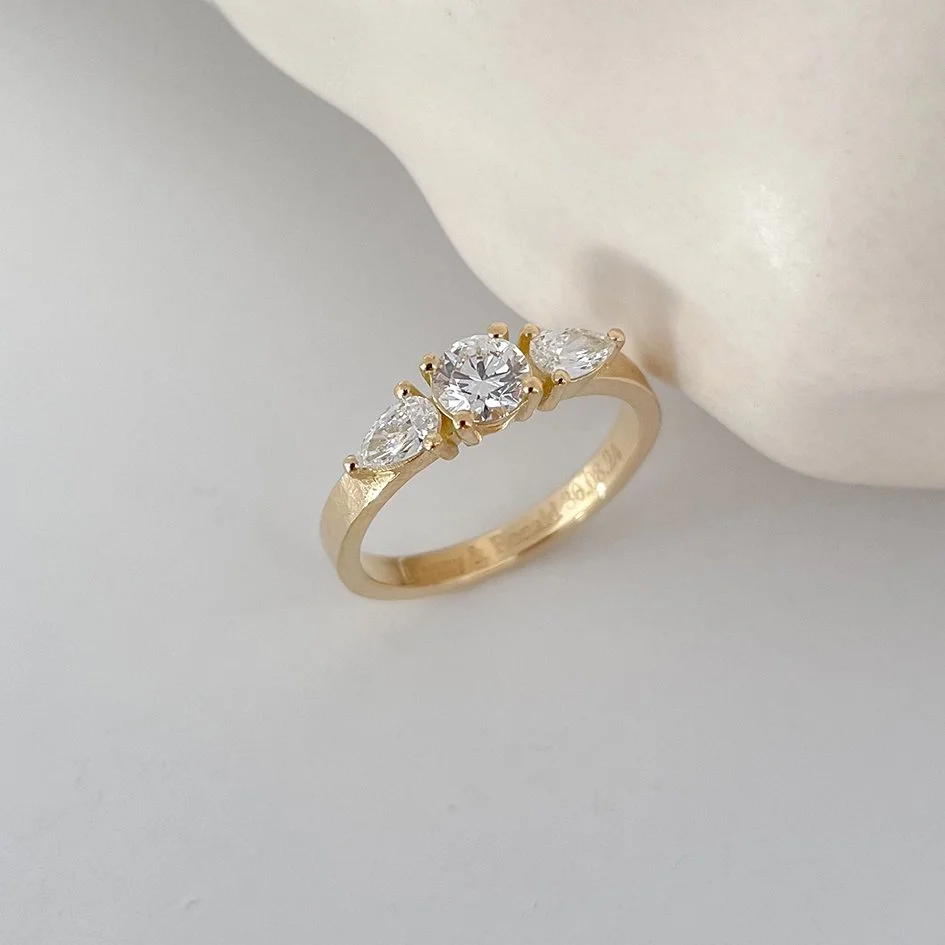 Handcrafted round engagement ring with smaller pear diamonds on the side. Handmade in recycled gold..
