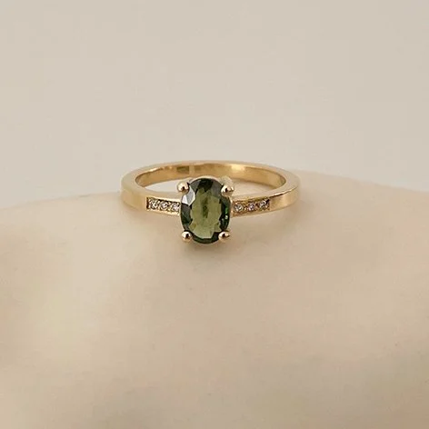 Handcrafted engagement ring with green gemstone and small diamonds in recycled gold