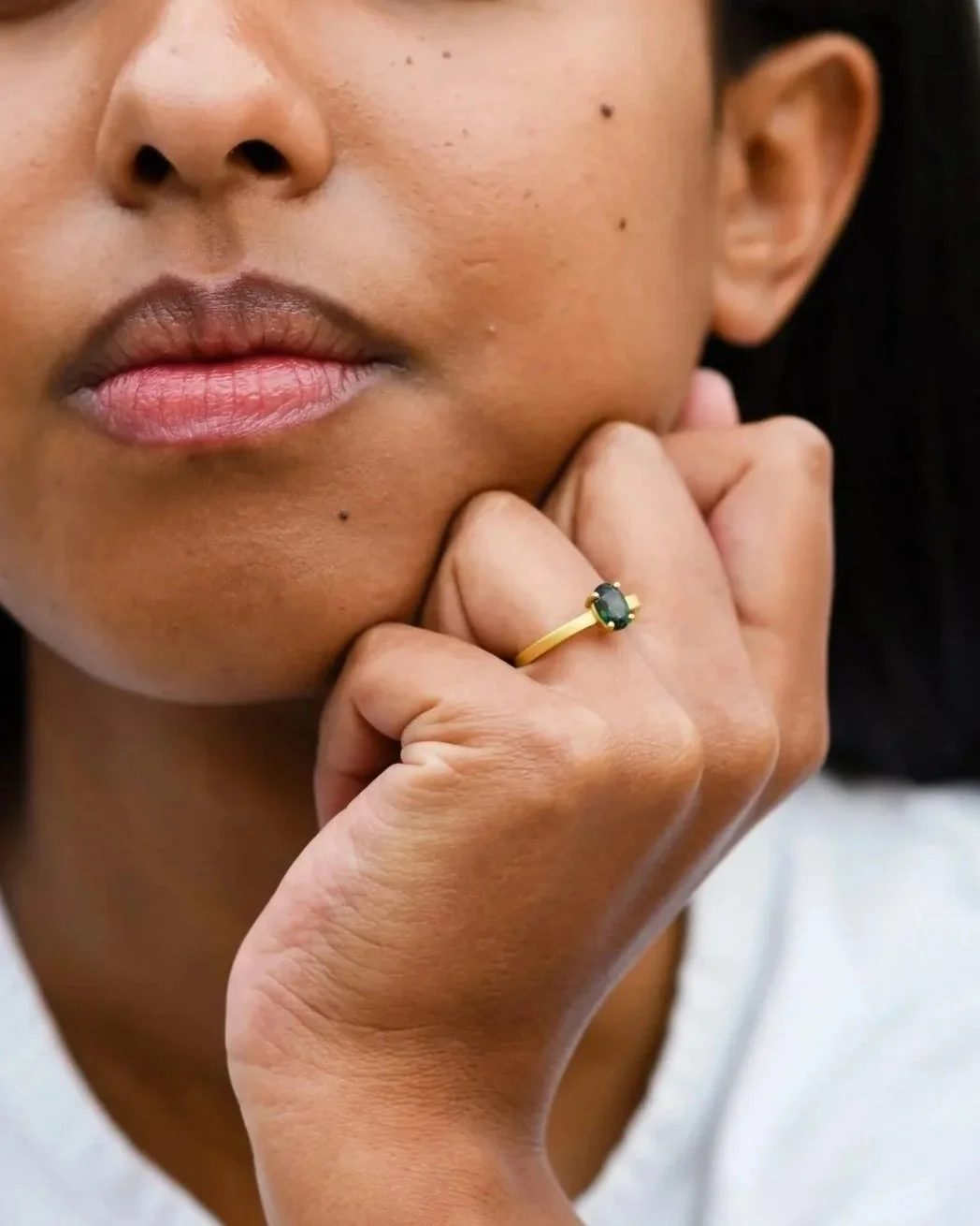 Groene edelsteen verlovingsring in geel goud gedragen door vrouw