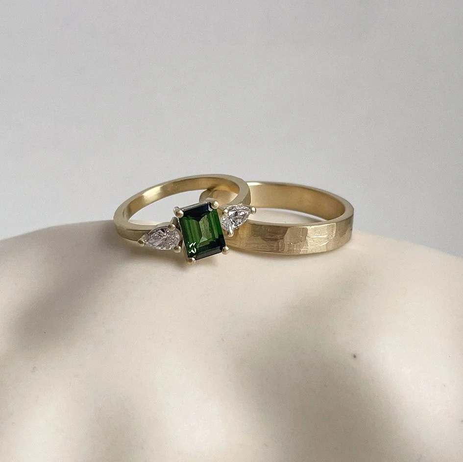 A striking wedding band with a gemstone and diamond, featuring a textured band for her, and the same textured band for him