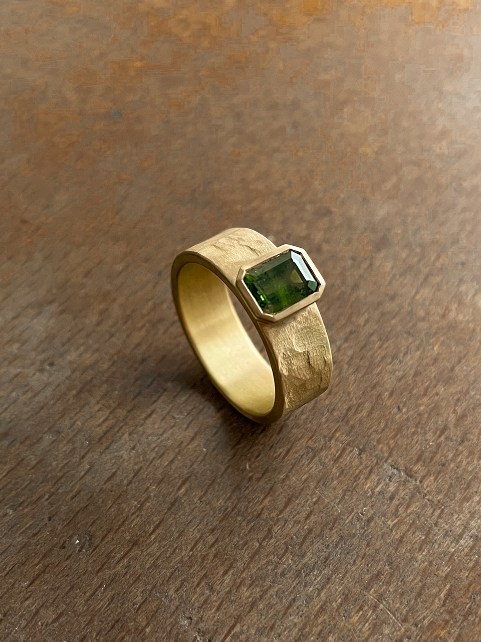 Een op maat gemaakte verlovings- en trouwring voor mannen, met een groene saffier