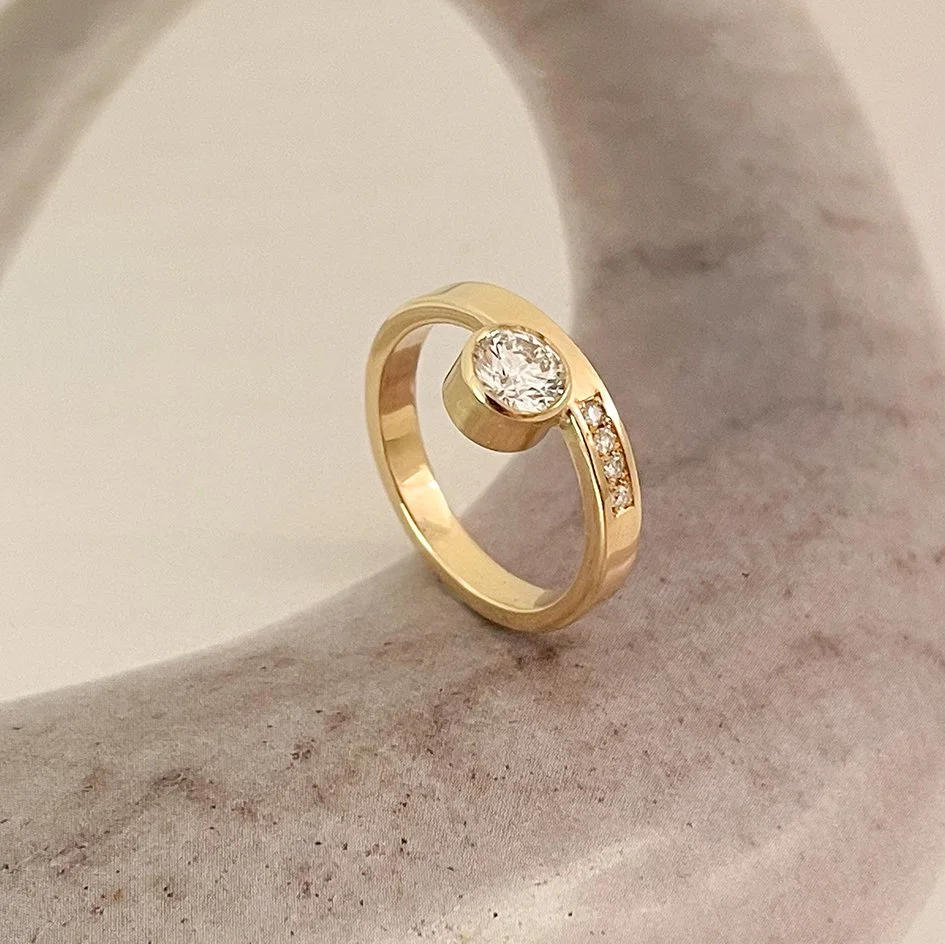 Modern and unique engagement ring with a large round diamond and a bezel setting