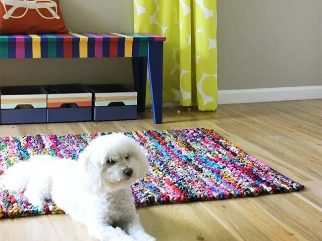 DIY painted Bench in different bright colors, with handmade curtains and a white poodle laying down on top of a colorful rug