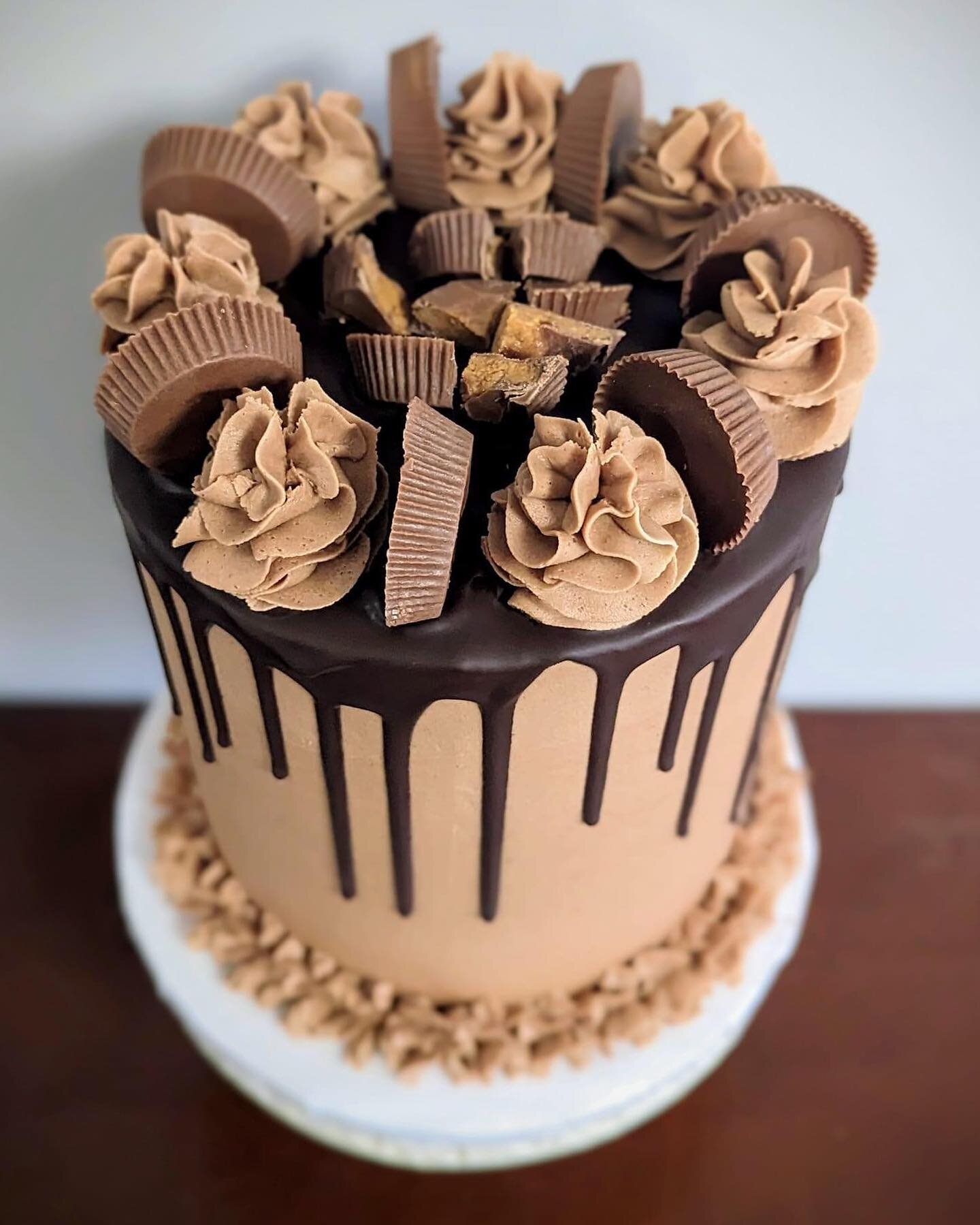 Chocolate cake with peanut butter frosting, a dark chocolate drip, and Reese peanut butter cups. YUM