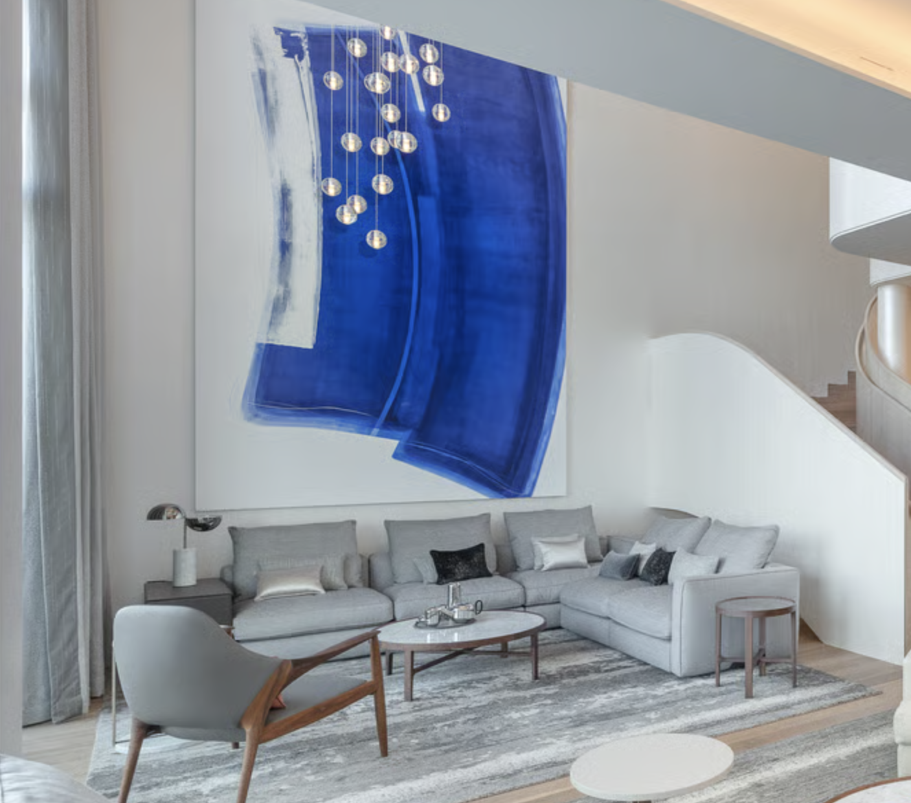 living room with grey sofa, grey anad wood armchair, large blue abstract artwork, grey silk rug and marble coffee table