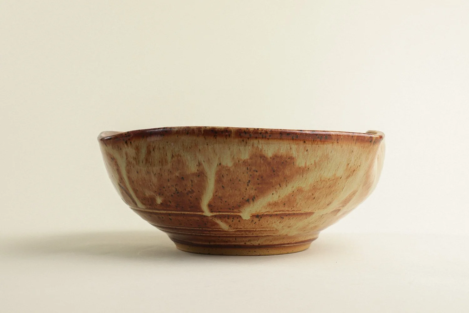 Handmade studio pottery bowl featuring a rustic, earthy-glazed swirl interior and a scalloped rim.