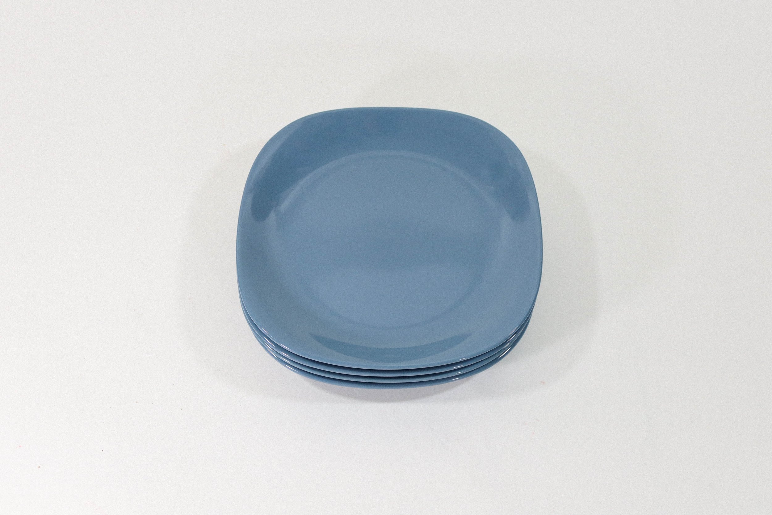 Set of four rounded square blue ceramic plates. Appears to be vintage, however there are no markings or branding.