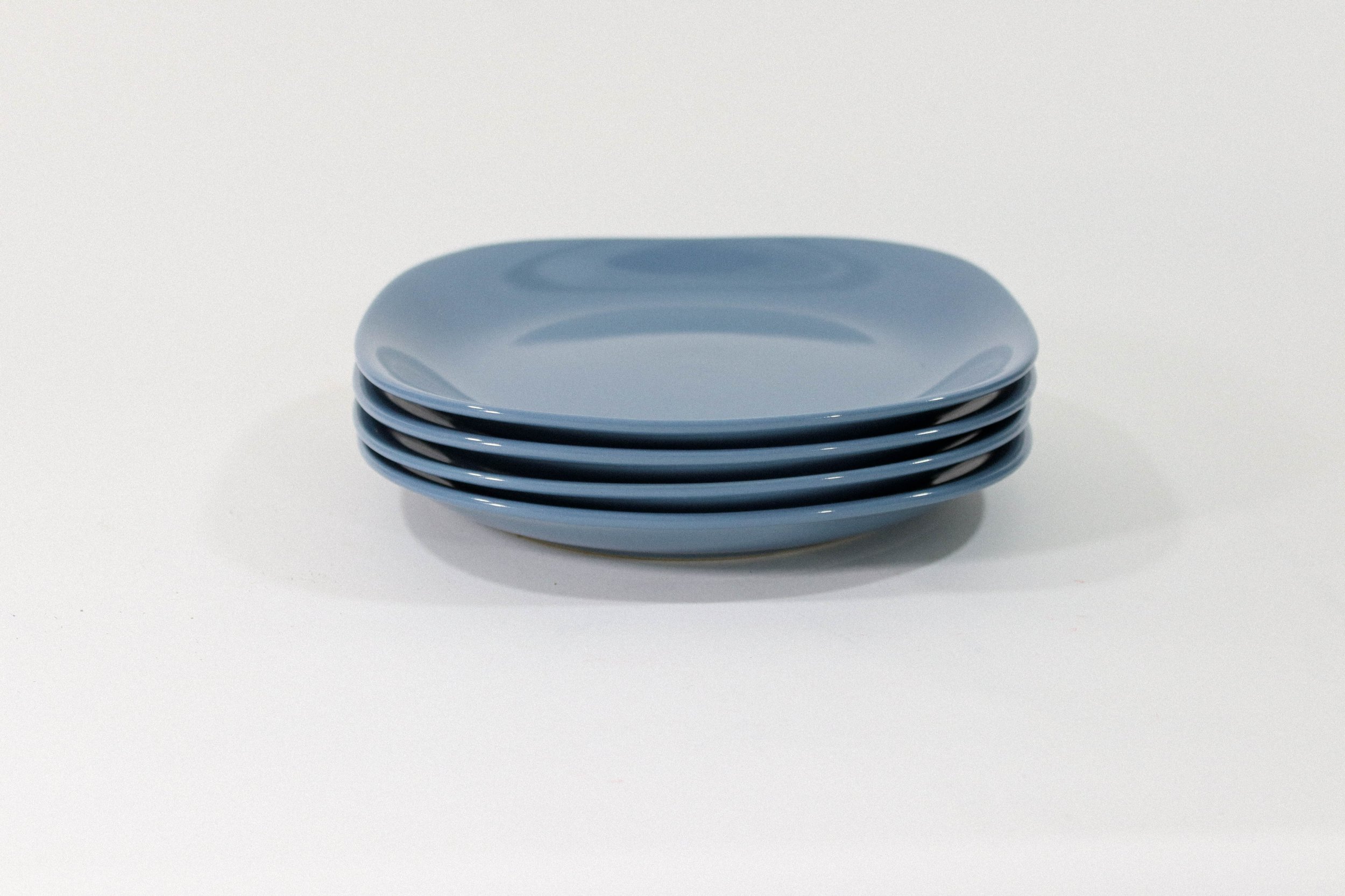 Set of four rounded square blue ceramic plates. Appears to be vintage, however there are no markings or branding.