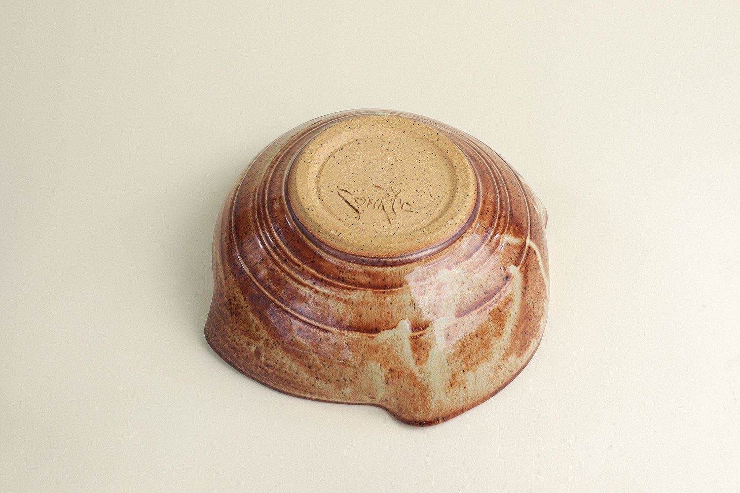 Handmade studio pottery bowl featuring a rustic, earthy-glazed swirl interior and a scalloped rim.