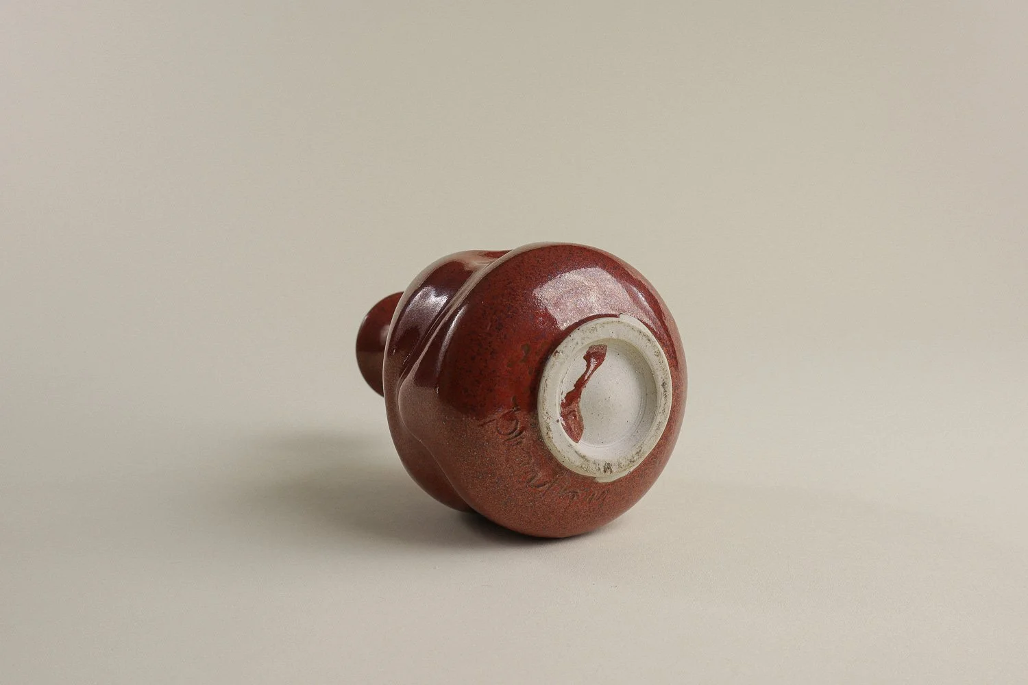 Handmade studio pottery bud vase featuring an organic, flowing form and reddish-brown glaze.