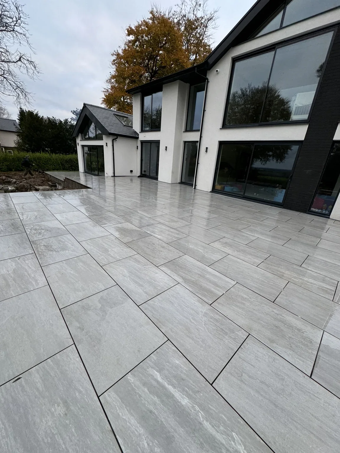 Completed porcelain tile patio beside a contemporary house, by LR Landscapes