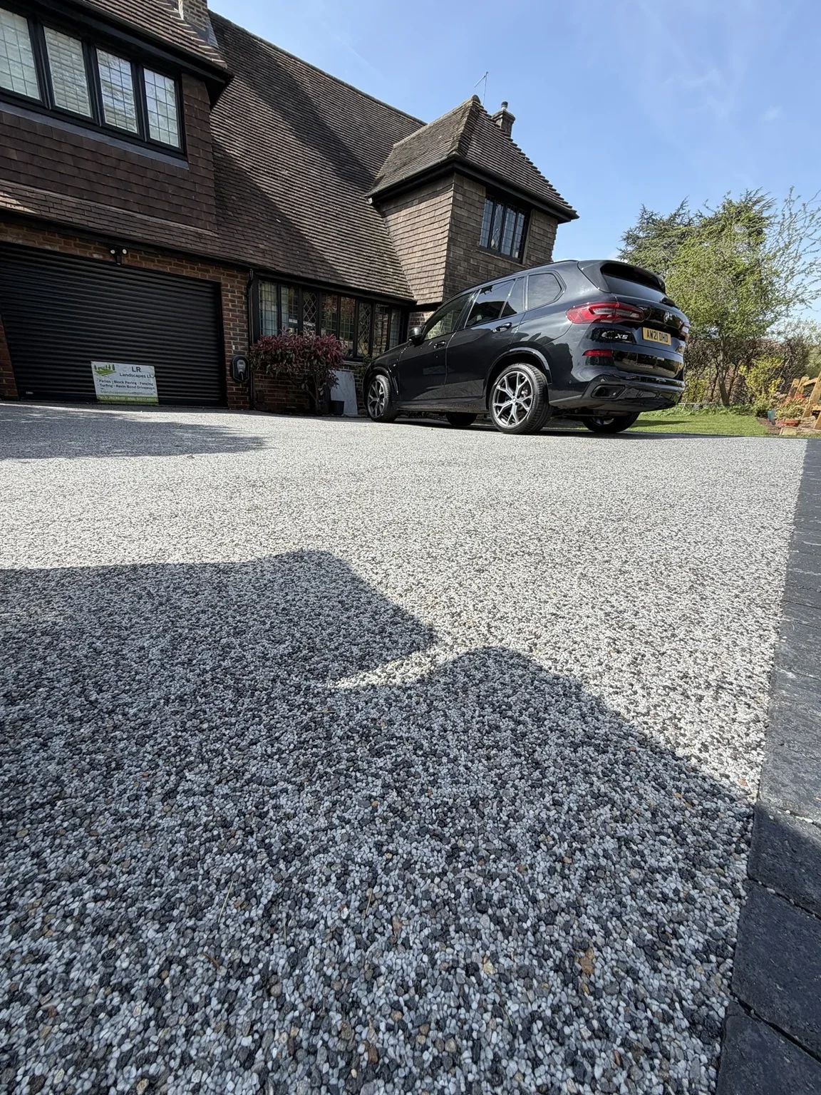 Resin bound driveway — the finished aggregate surface extends across the front of the house, with defined edges around the entrance and parking area.