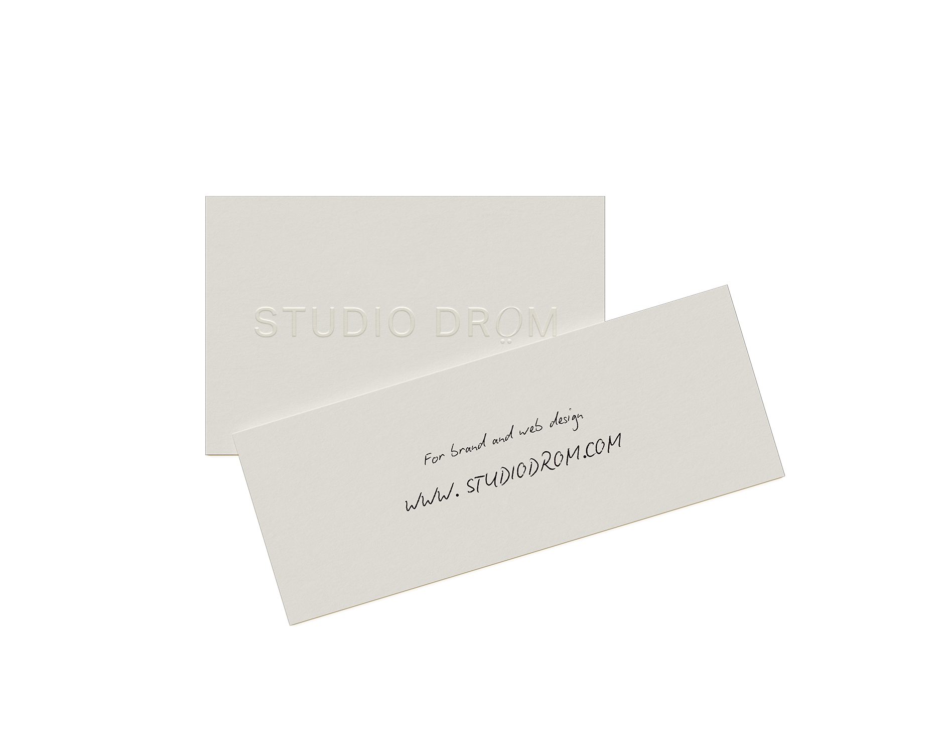 Une carte de visite blanche sur laquelle figure l'adresse du site web écrite à la main, placée derrière un dossier fermé en relief portant l'inscription « STUDIO DROM », symbolisant une recommandation de type bouche-à-oreille pour les services de conception web de Studio Dröm.
