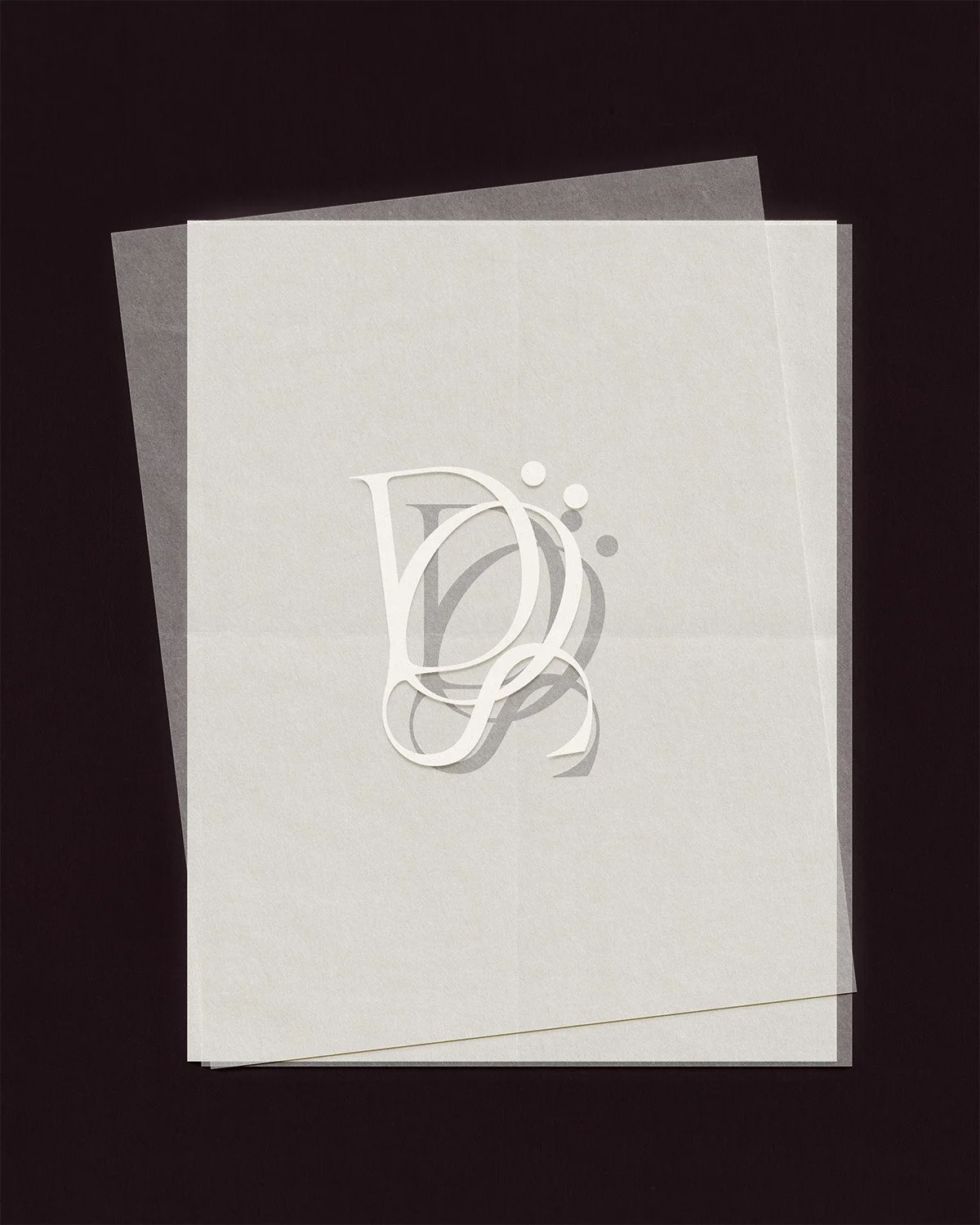Élégante carte de vœux blanche avec les initiales du monogramme « D » et « S » en relief sur un fond sombre, représentant l'identité de marque de Studio Dröm et son travail de conception d'identité visuelle personnalisée.