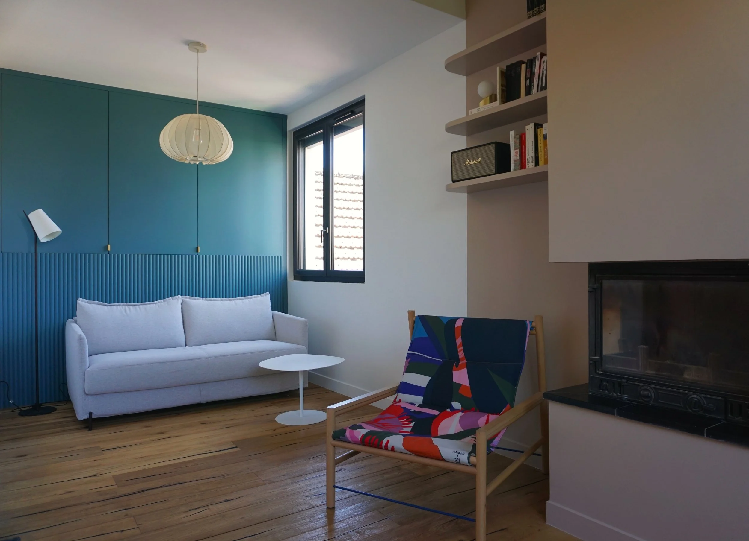 Chambre d'amis canapé gris mur bleu vert cheminée mur beige rosé