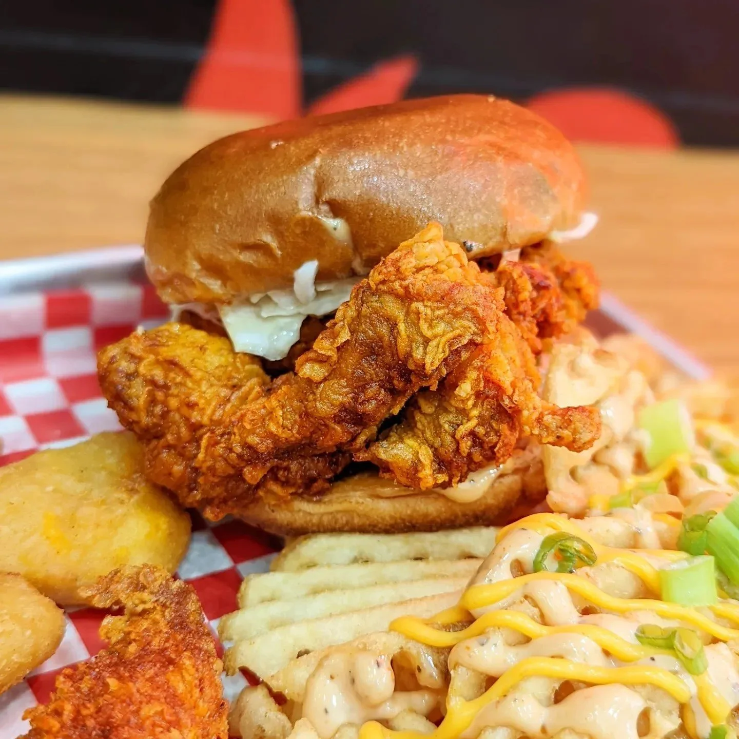 Close-up of a fried chicken sandwich with a bun, fried chicken filet, egg, and bread.