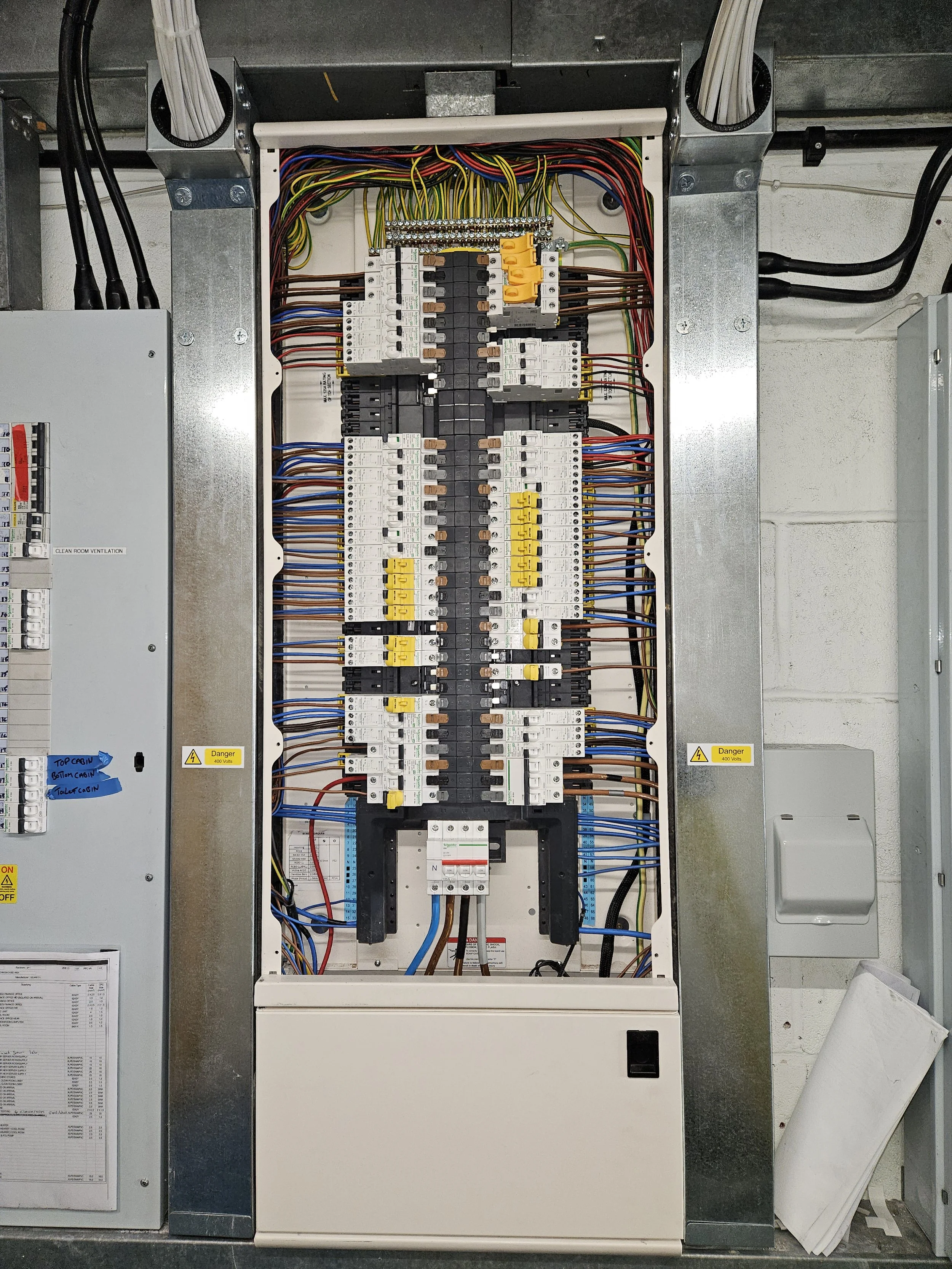 Electrical panel with numerous circuit breakers, wires, and some warning labels.