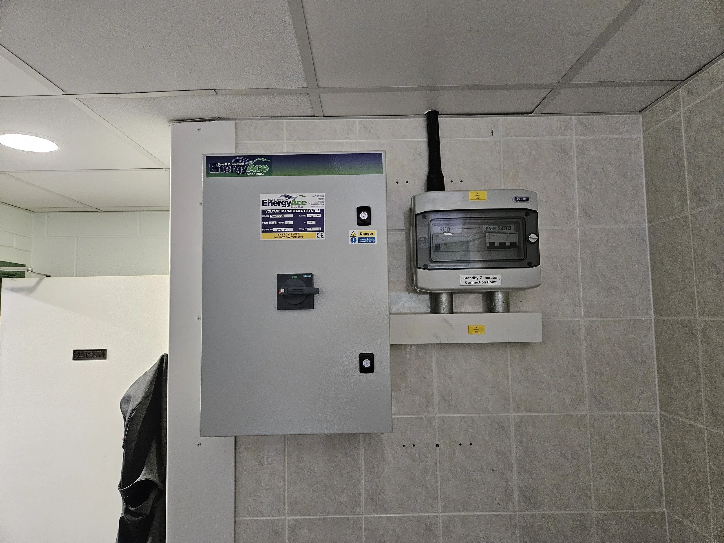 Electrical control panel and connection box mounted on a tiled wall in a utility room.