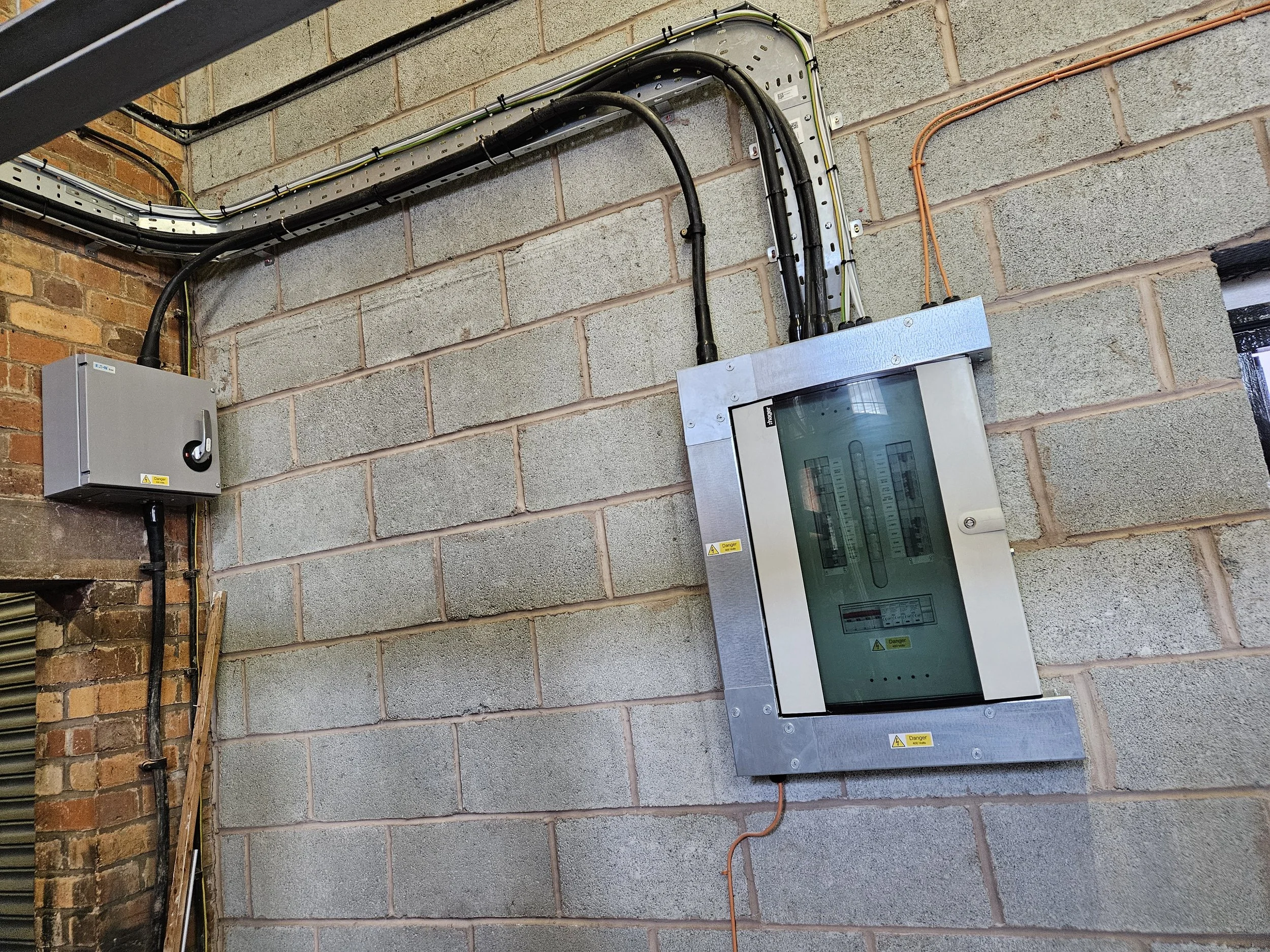 Electrical panel and wiring mounted on a cinder block wall.