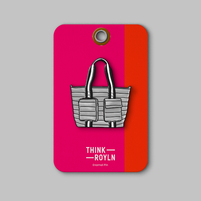 Enamel pin shaped like a gray handbag with black handles, attached to a pink and orange card labeled 'THINK ROYLN'.