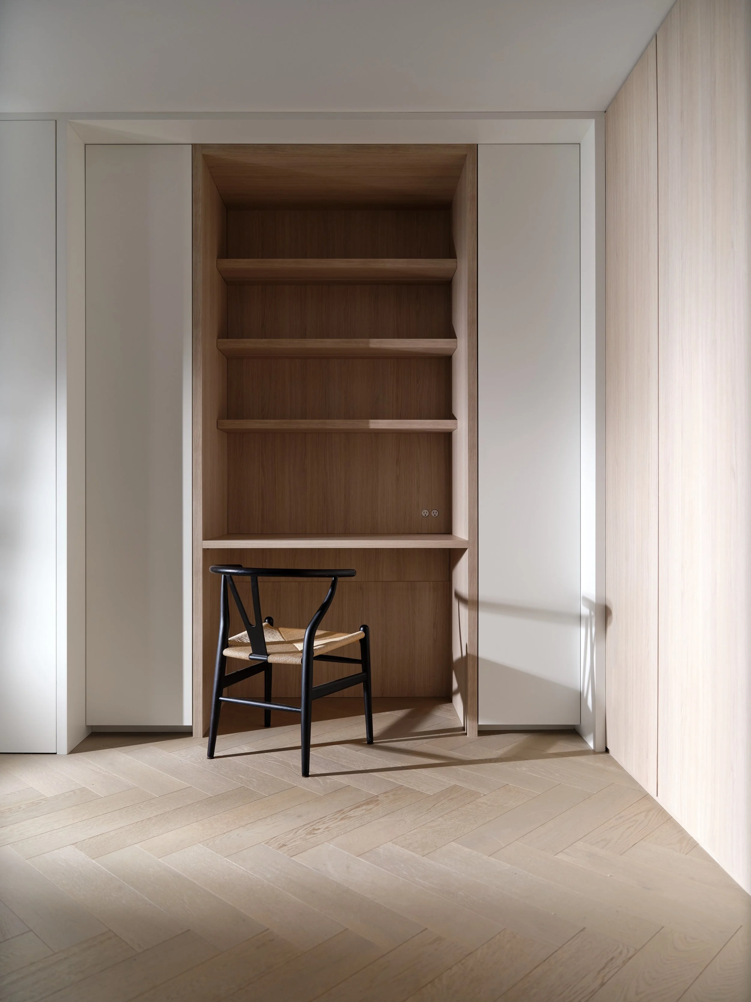 Shangri-La Residences: Den

An extension of the white oak from the entry into a full floor-to-ceiling millwork wrap &mdash; concealed storage, a hidden laundry, and an integrated office nook with open shelving and desk, finished with soft LED lightin